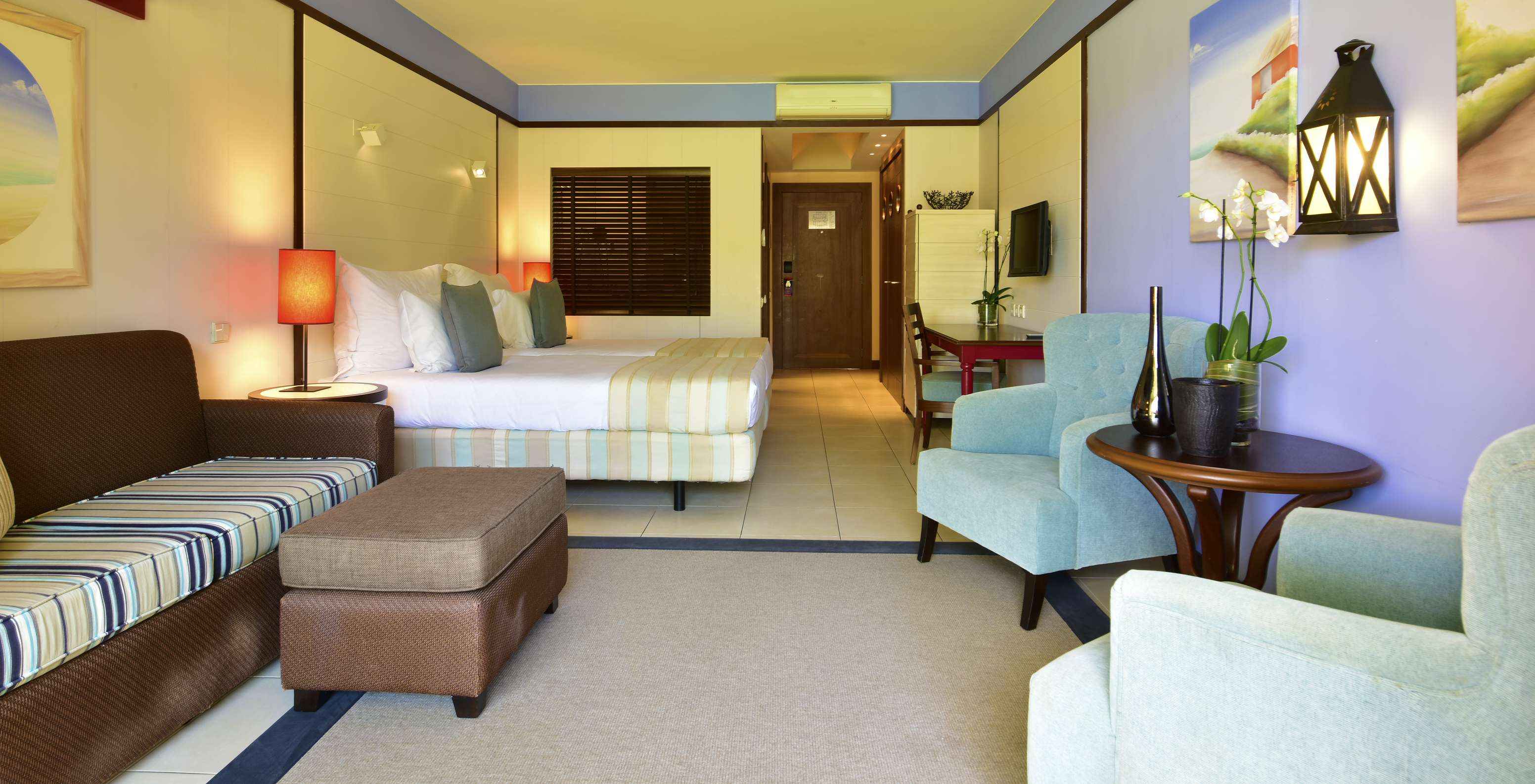 Le Double Vue Piscine du Pestana Porto Santo All Inclusive a un canapé, deux fauteuils, deux lits, télévision et bureau