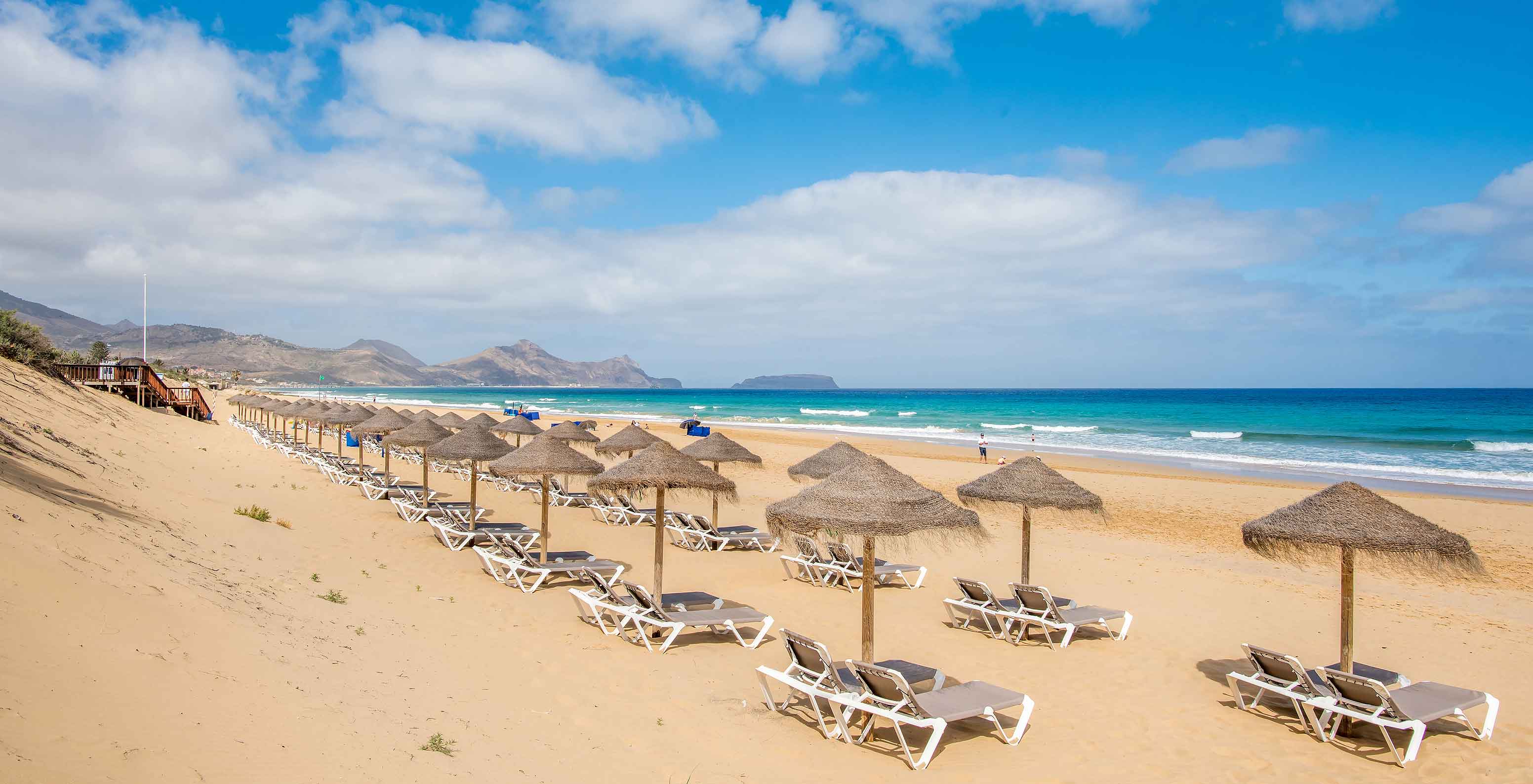 Beach Bar, Resort 5 étoiles à Porto Santo a une plage avec mer calme et bleue, et divers auvents