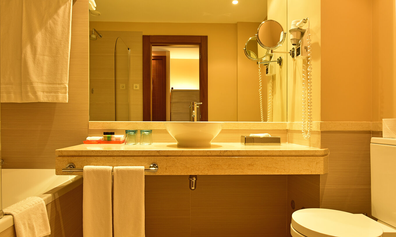 Le Double Classique du Pestana Porto Santo All Inclusive a une salle de bain avec lavabo, miroir, toilettes et serviettes