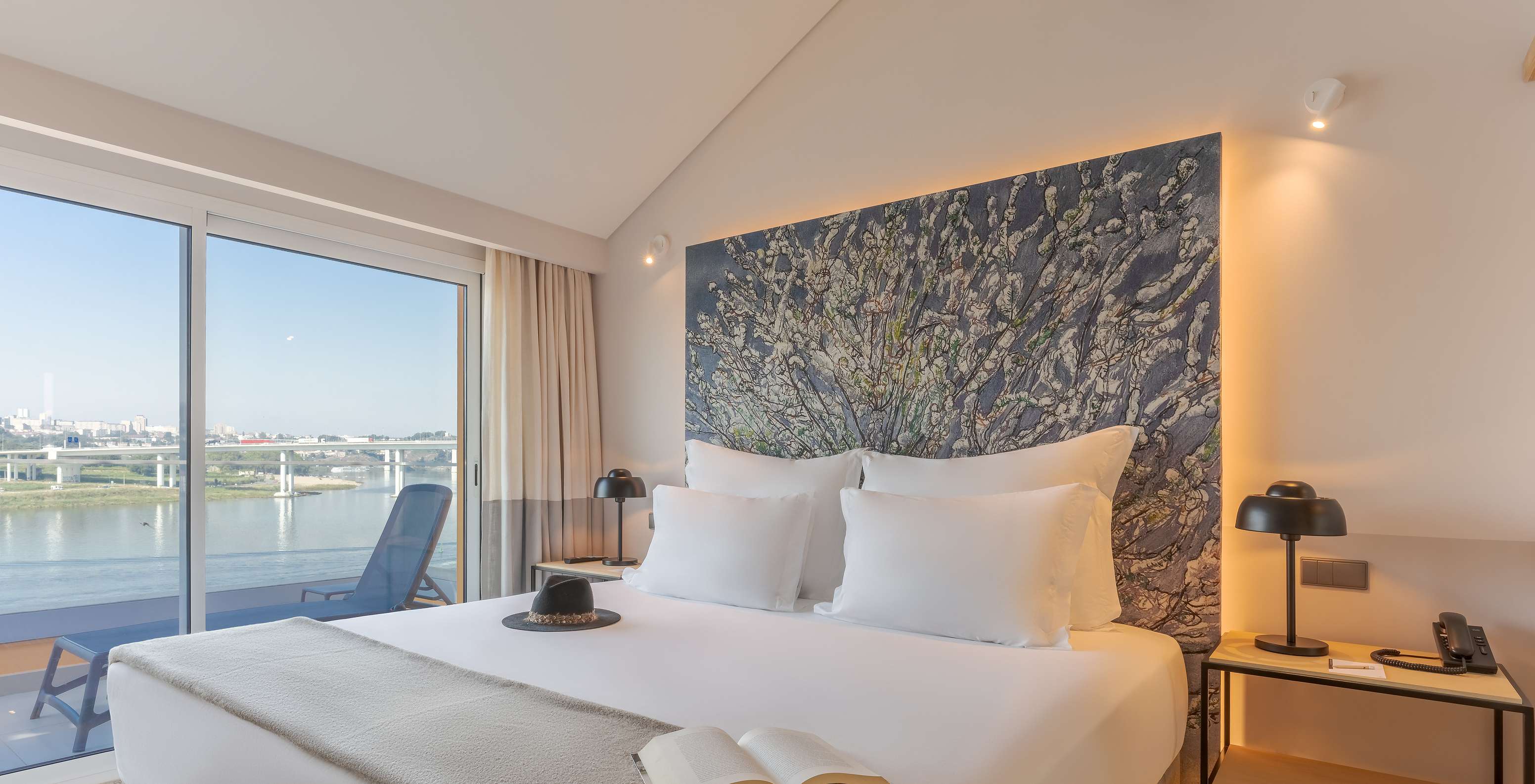 La Suite Douro du Pestana Douro Riverside a un lit double avec table de nuit et balcon avec vue sur le fleuve