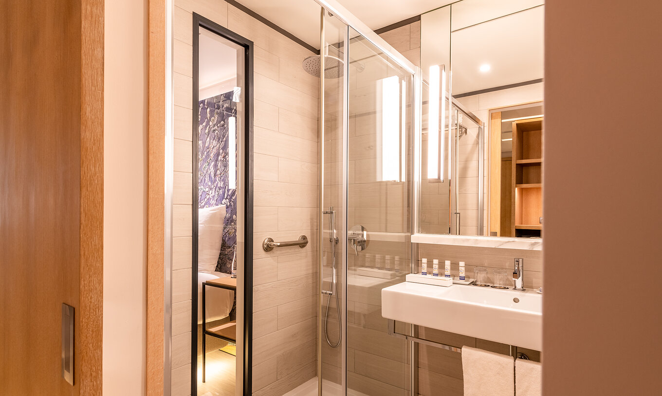 La chambre Deluxe River View du Pestana Douro Riverside a une salle de bain avec lavabo, miroir et douche