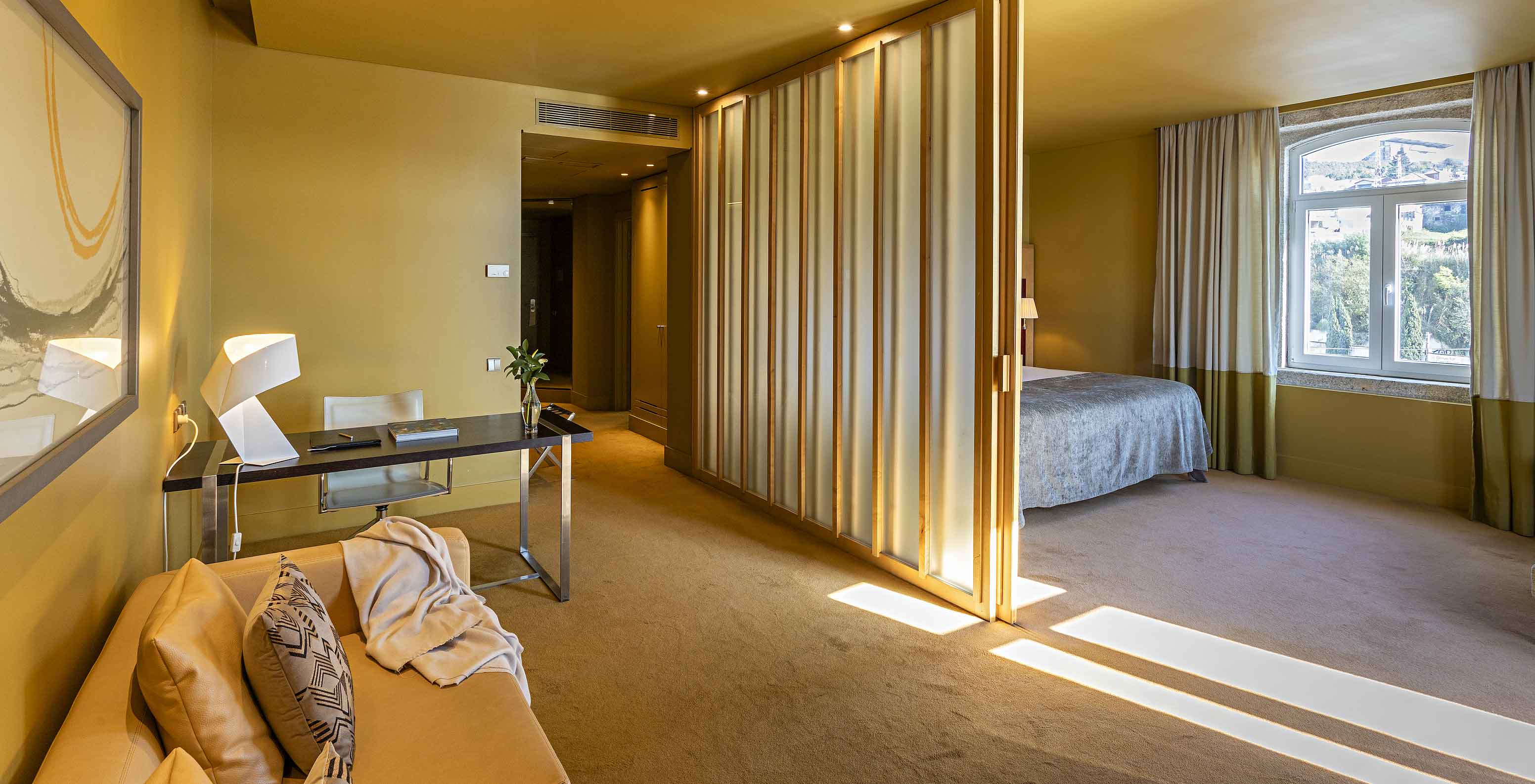 La Suite Standard comprend un lit double avec cloison vers Le salon avec canapé et bureau