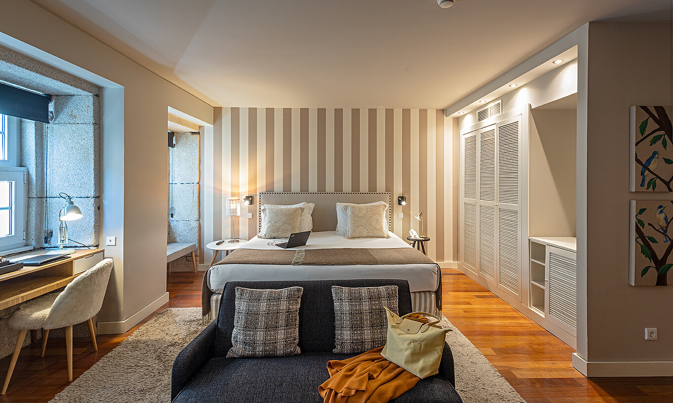 La Heritage Suite du Pestana Vintage Porto dispose d'un lit double, d'un canapé, d'un bureau et d'une armoire blanche