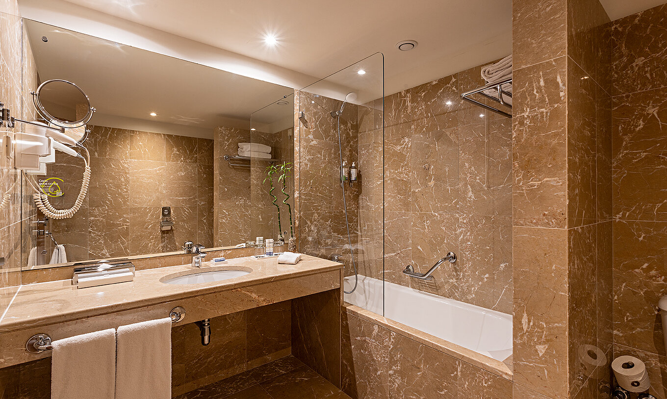 La Suite Grand View du Pestana Vintage Porto dispose d'une salle de bain avec des murs en marbre brun et une baignoire