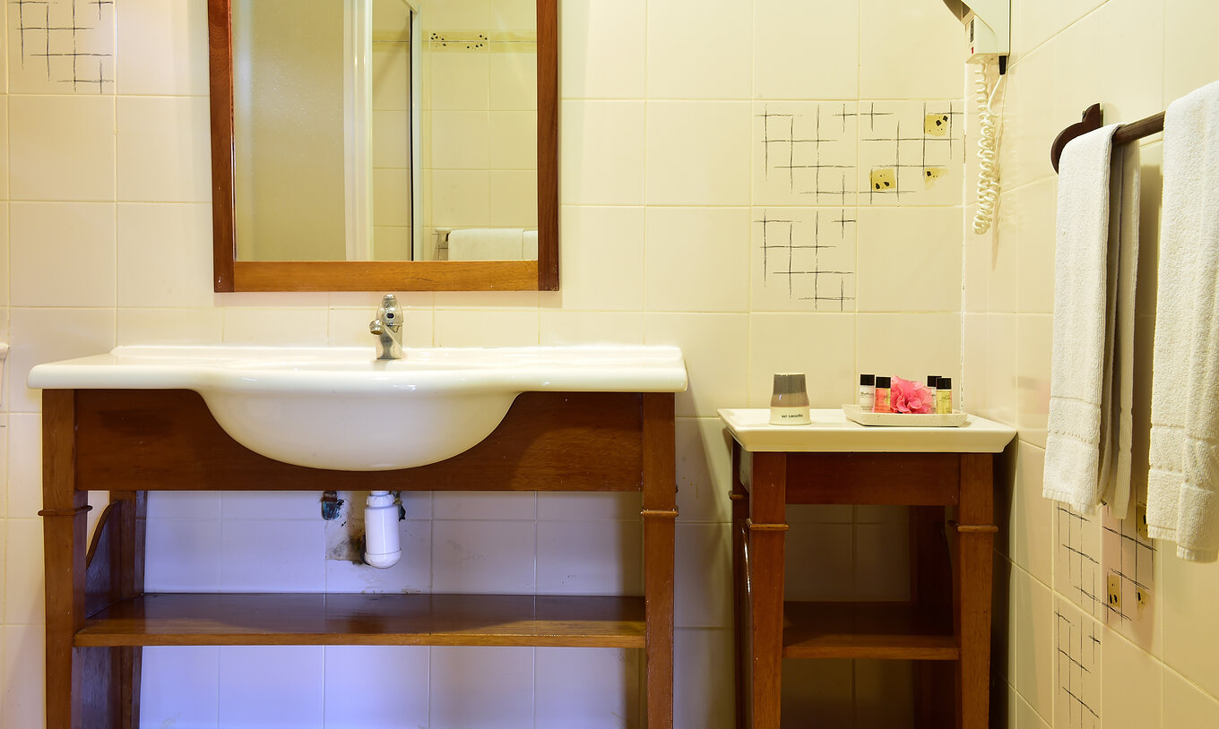 La Suite Standard du Pestana Equador Ilheu das Rolas a une salle de bain avec une table et un lavabo avec miroir