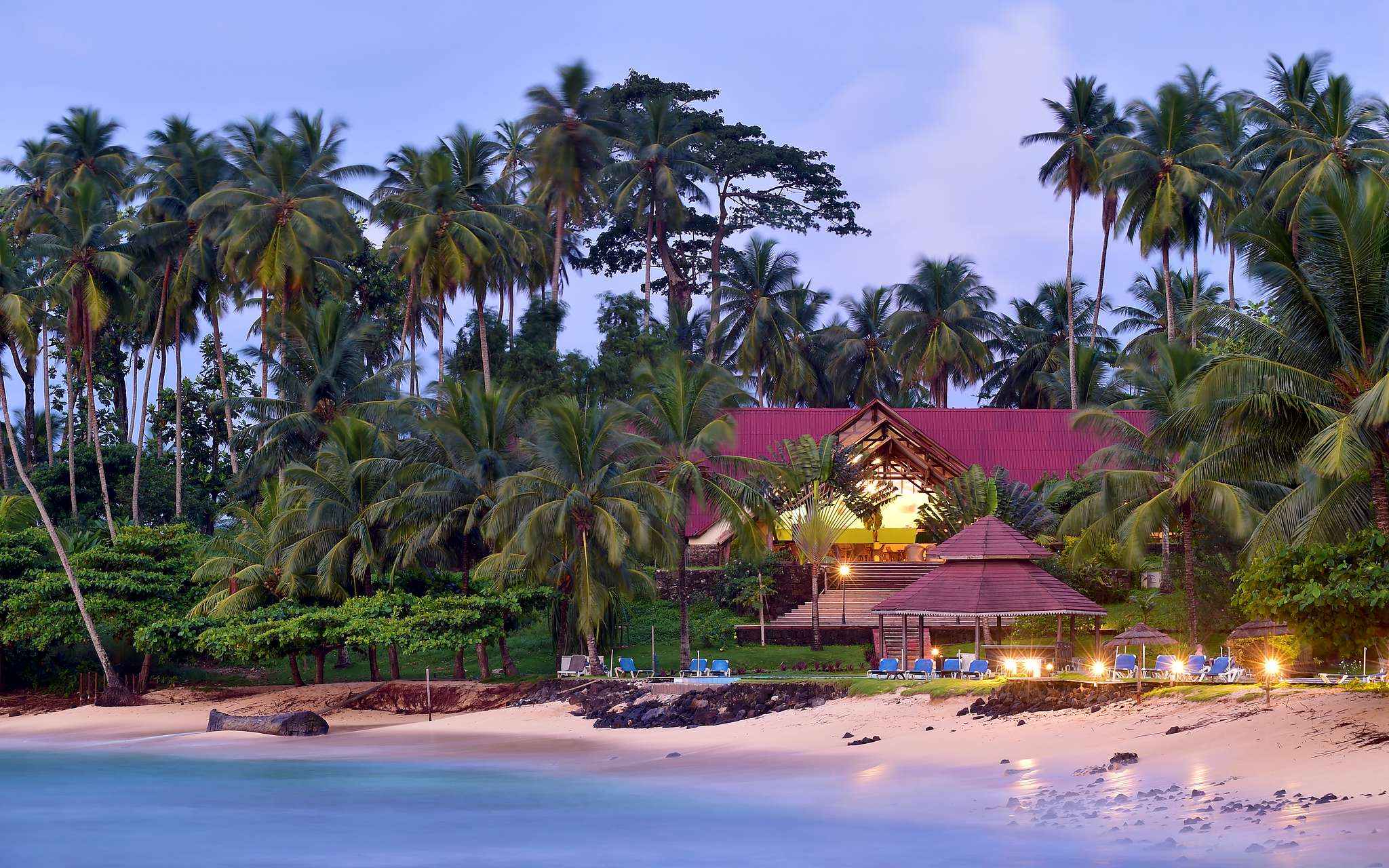 Plage et bâtiment avec transats et palmiers du Pestana Equador, hôtel sur l'île de Rolas, à São Tomé