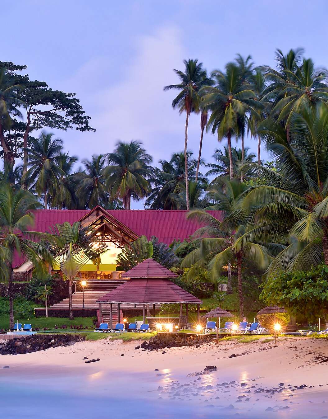 Plage et bâtiment avec transats et palmiers du Pestana Equador, hôtel sur l'île de Rolas, à São Tomé