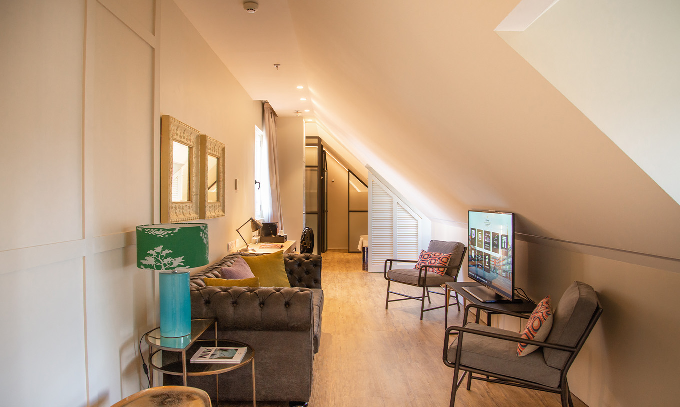 La Suite Plaza Mayor du Pestana Plaza Mayor Madrid a un salon avec canapé, fauteuils, télévision et tableaux au mur