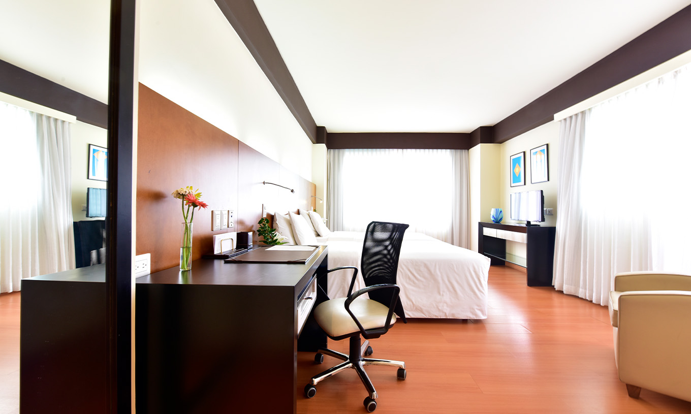 La King Junior Suite du Pestana Caracas a un lit double, un bureau avec une chaise ergonomique et une poltrona