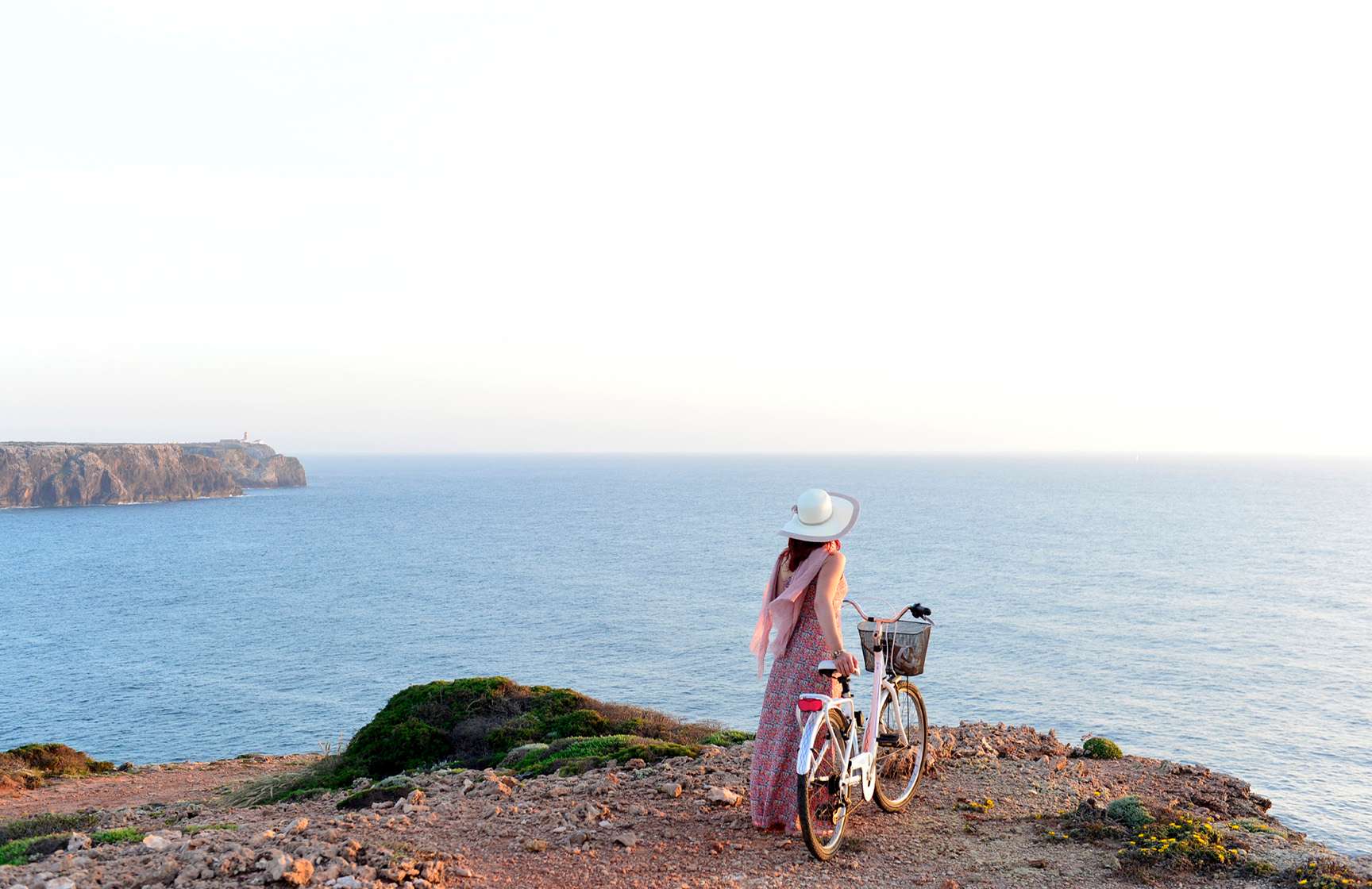 Femme se promenant avec un vélo à la main, le long des falaises de la côte portugaise, fourni par Pousadas de Portugal