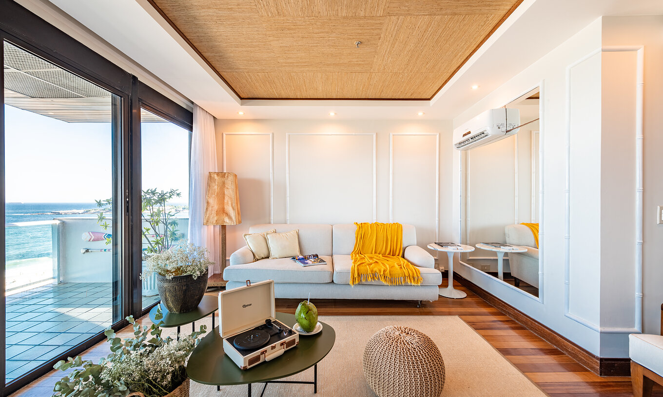 De Presidentiële Suite van Pestana Rio Atlântica heeft een woonkamer met houten plafond, witte bank en uitzicht op de zee