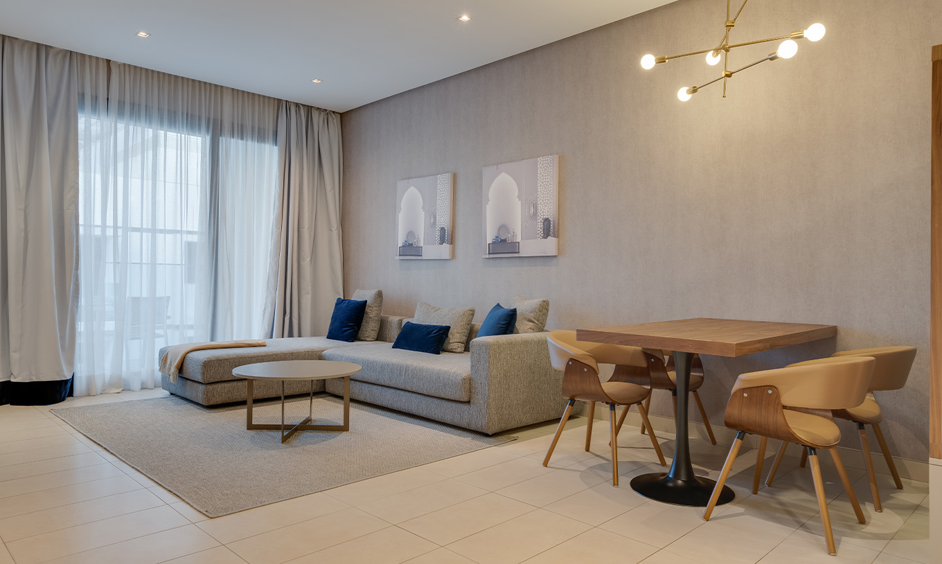 De Familiesuite Premium van Pestana Casablanca heeft een grote grijze bank met een chaise longue naast het raam.