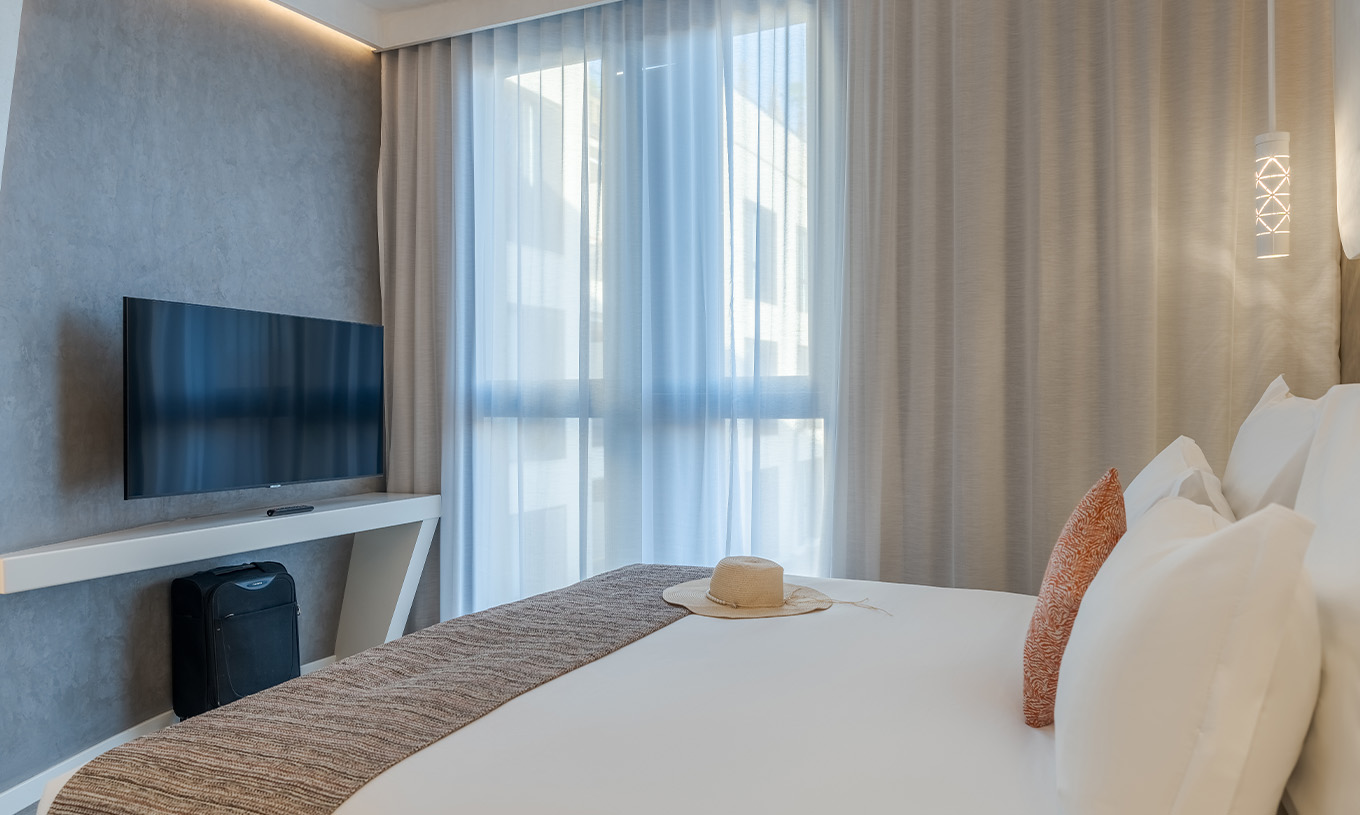 De CR7 Suite van Pestana CR7 Marrakech heeft een kamer met tweepersoonsbed, televisie en een raam met gordijnen