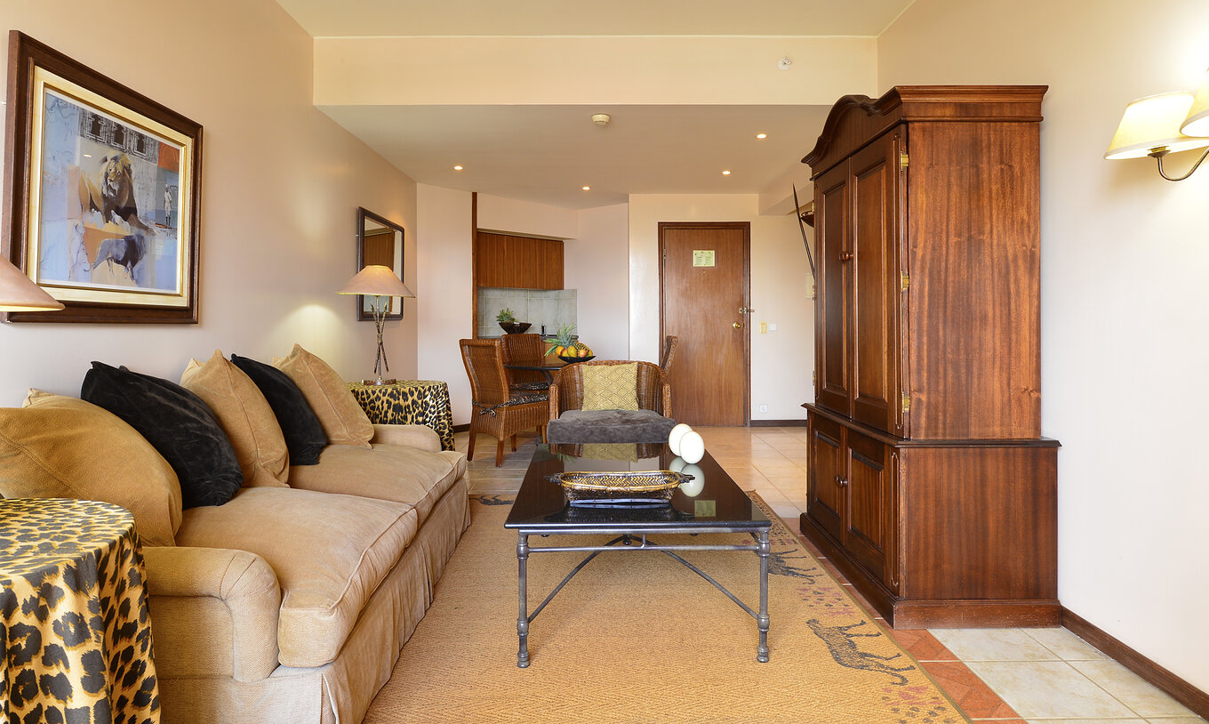 De Luxe Suite van Pestana Rovuma heeft een woonkamer met beige bank en twee tafels met luipaardprint