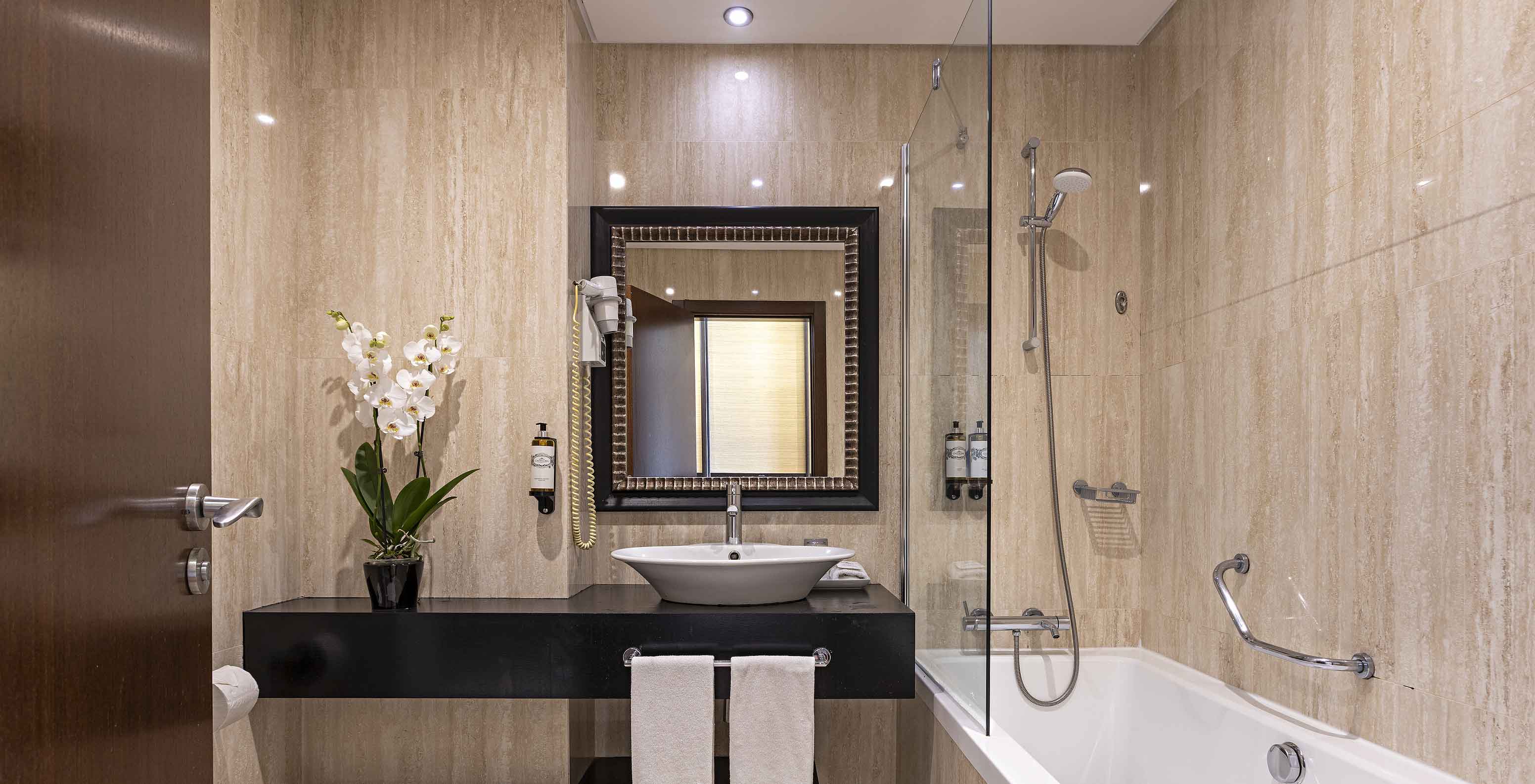 Het Cliff Family in Pestana Alvor Praia heeft een moderne badkamer met bad, wastafel, toilet, spiegel en bloemen