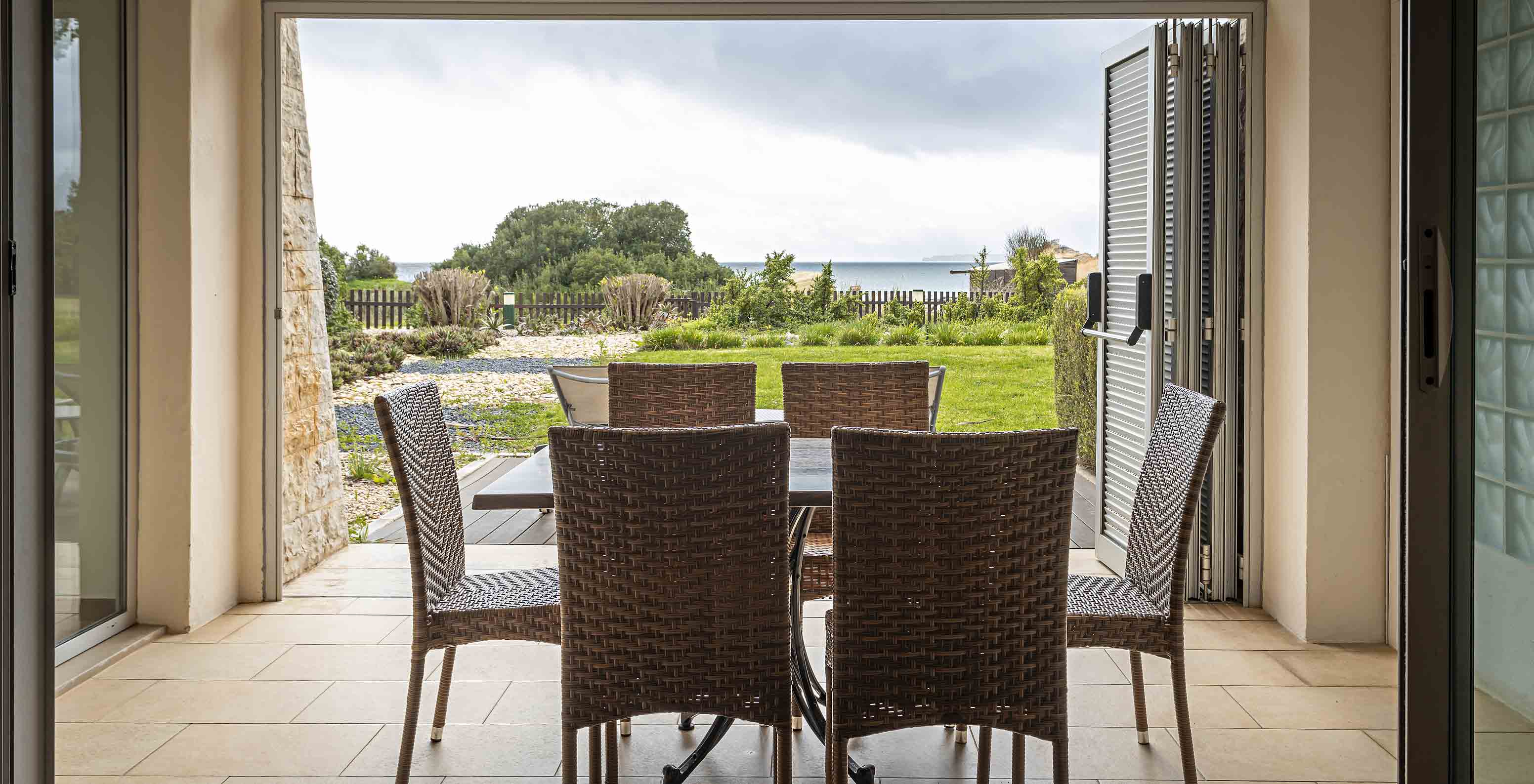 De Cliff Suite T2 in Pestana Alvor Praia heeft een veranda met een tafel en stoelen en een tuin met uitzicht op het strand