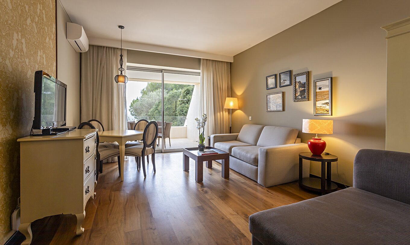 De Cliff Suite T1 in Pestana Alvor Praia heeft een woonkamer met 2 banken, een dressoir met tv, een eettafel en stoelen