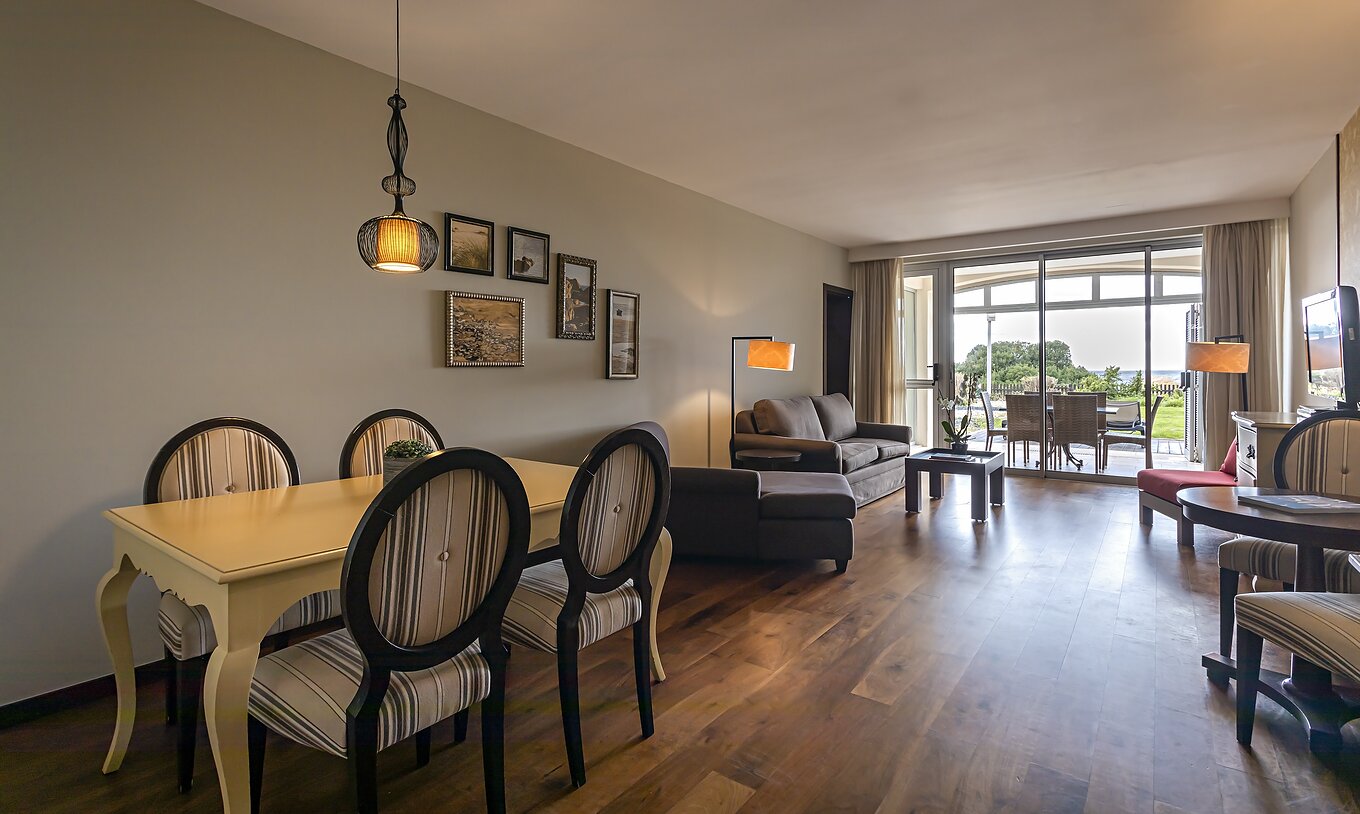 De Cliff Suite T2 in Pestana Alvor Praia heeft een woonkamer met twee banken, een televisie, een eettafel en een veranda