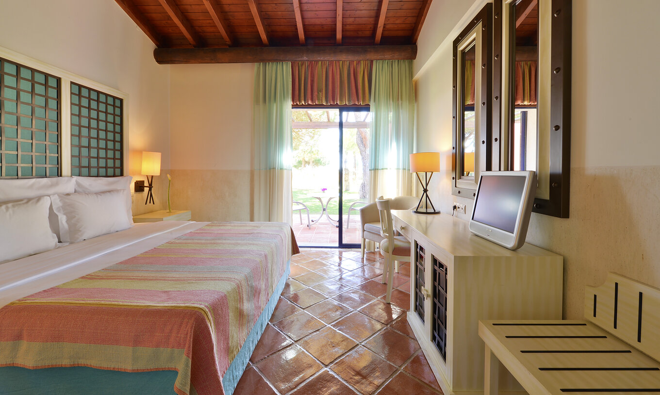 Suite uitzicht tuin Vila Sol van Pestana Vila Sol - Vilamoura heeft een slaapkamer met tweepersoonsbed, spiegel en balkonraam