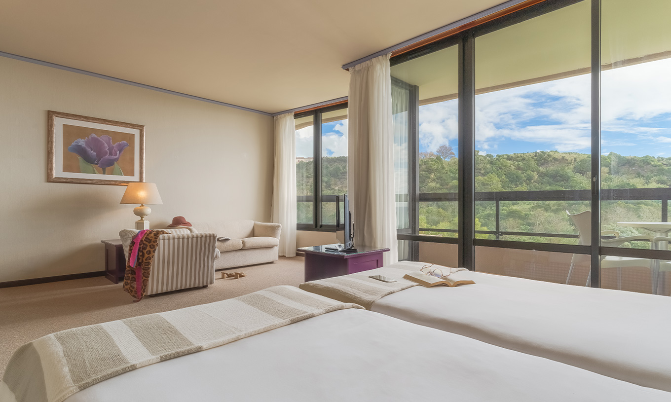 Junior Suite Tuinzicht van Pestana Bahia Praia heeft mooi uitzicht op groene landschap met toegang tot balkon