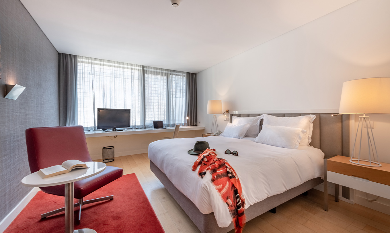 De Classic Room van Pestana Cidadela Cascais heeft een tweepersoonsbed, televisie, een rood tapijt en een groot raam