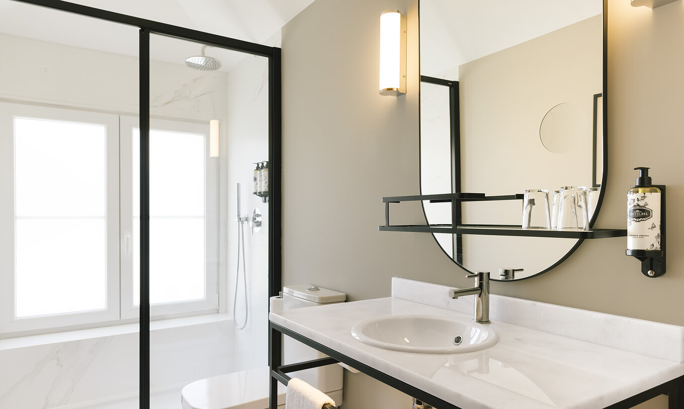 De Junior Suite van Pestana Rua Augusta Lisboa heeft badkamer met wastafel in wit marmer, spiegel, toilet en douche