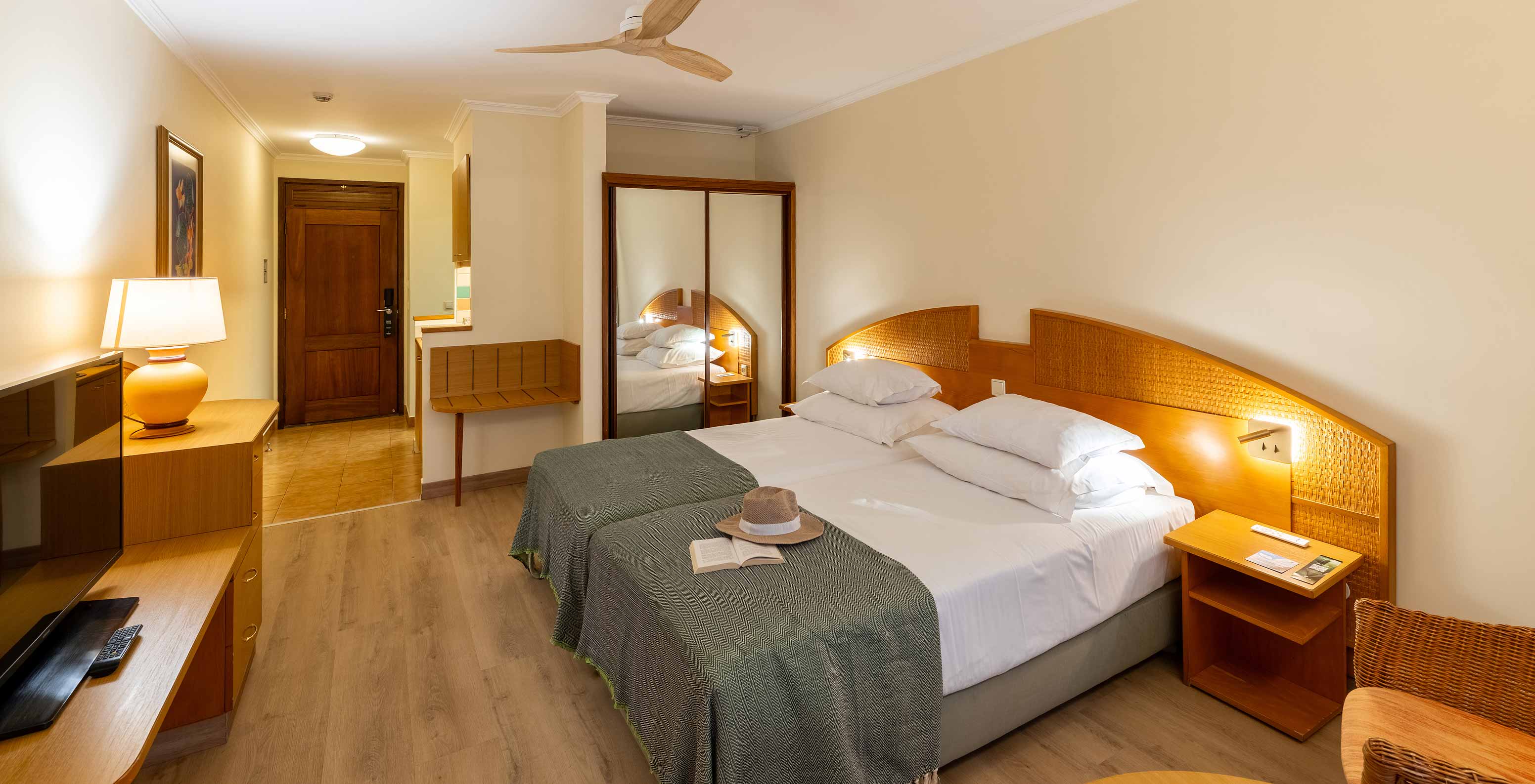 De Classic Pool View van het Pestana Ocean Bay All Inclusive heeft een tweepersoonsbed met een groene sprei