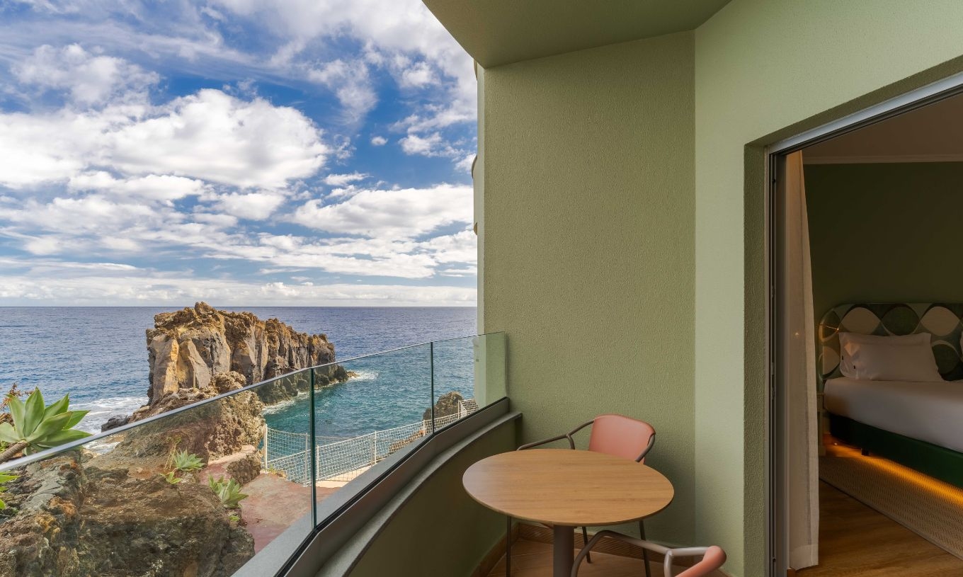 De Superior Zijdelings Zeezicht kamer van het Pestana Vila Lido Madeira heeft een balkon met een tafel en stoelen.
