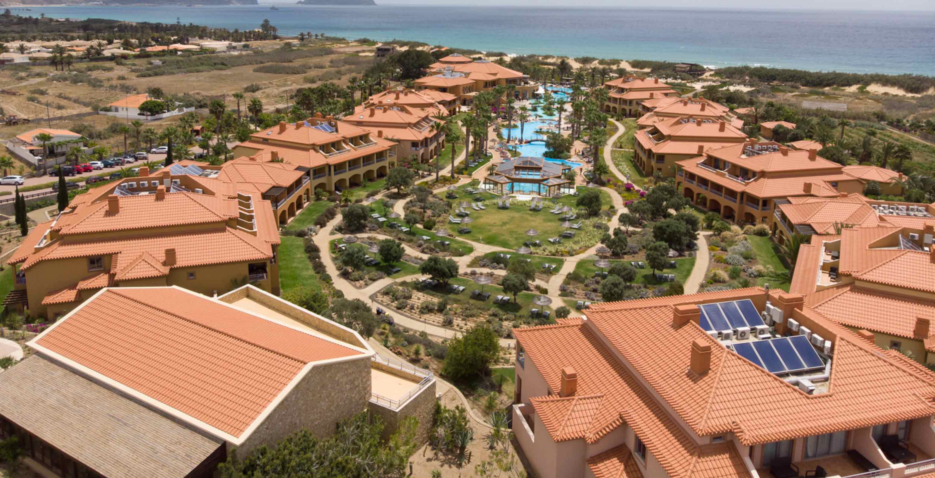 Dronebeeld van Pestana Porto Santo All Inclusive, met verschillende villa’s rond het zwembad en het groen