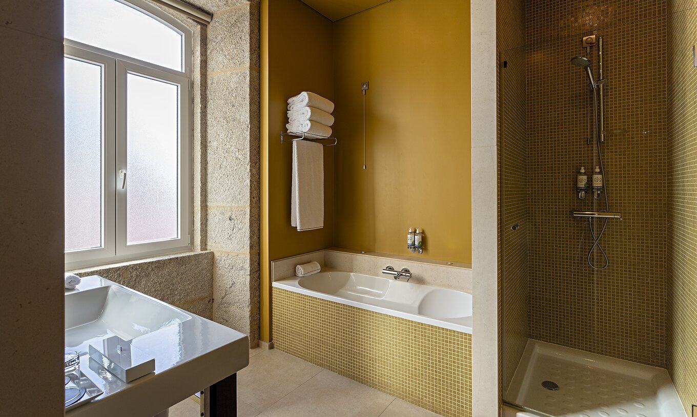 De Suite Nasoni heeft een badkamer met gele tegels, bad en douchegedeelte