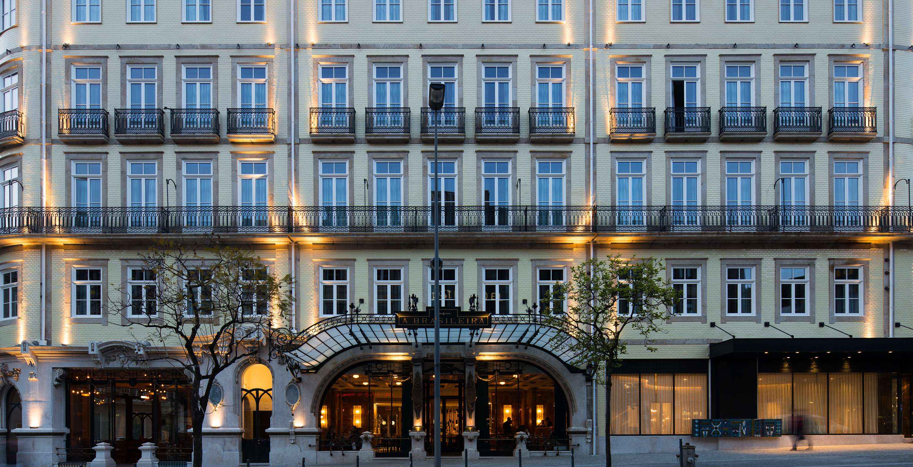 De verlichte gevel van het Pestana Porto - A Brasileira hotel toont een indrukwekkende architectuur met klassieke details