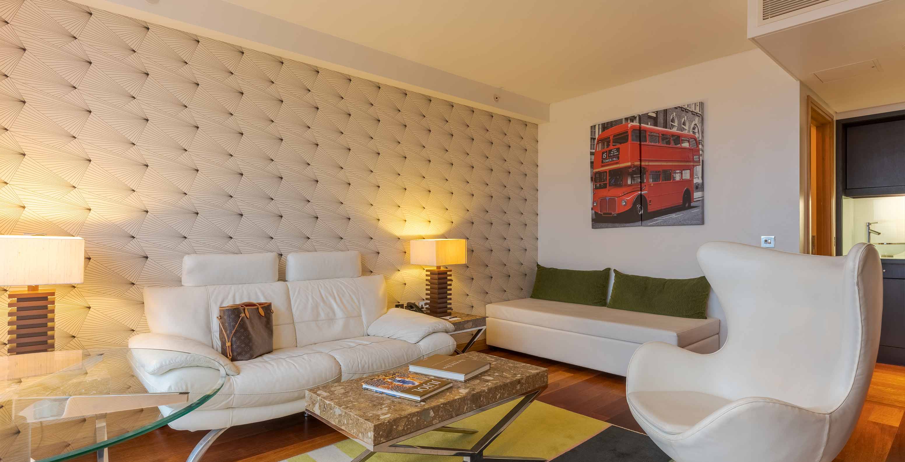 De Executive One Bedroom Suite van Pestana Chelsea Bridge heeft bank, poef, salontafel, glazen tafel en fauteuil