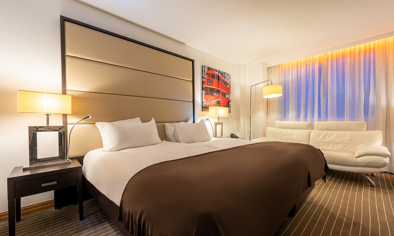 De Premium Twin van Pestana Chelsea Bridge heeft twee bedden, nachtkastje, bank, lampen en ramen met gordijnen