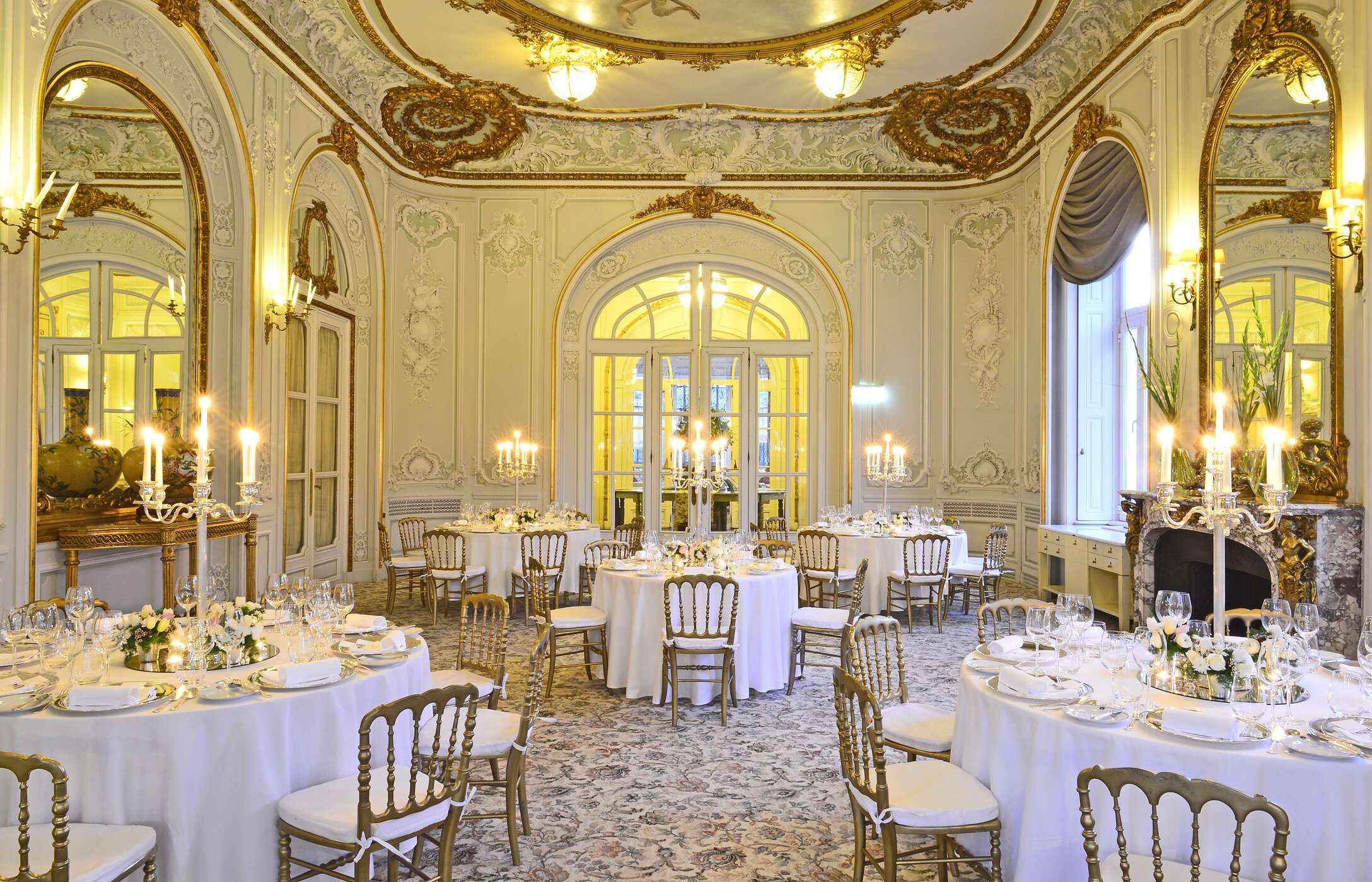 Bruiloft in een elegante zaal, tapijt met patroon, muren met gouden details en tafels met bloemenarrangementen