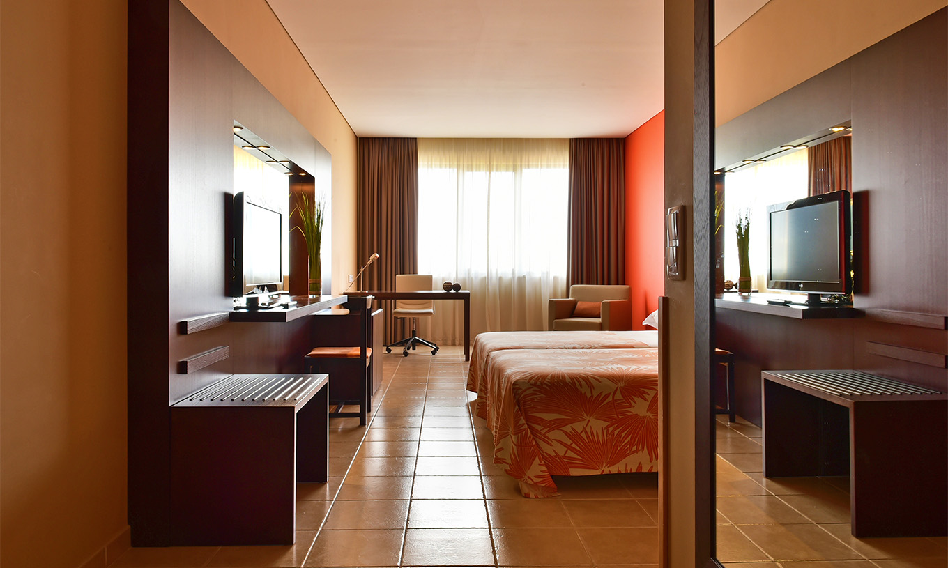 A Suite do Pestana Tropico conta com duas camas individuais, secretária, televisão, e um cadeirão 