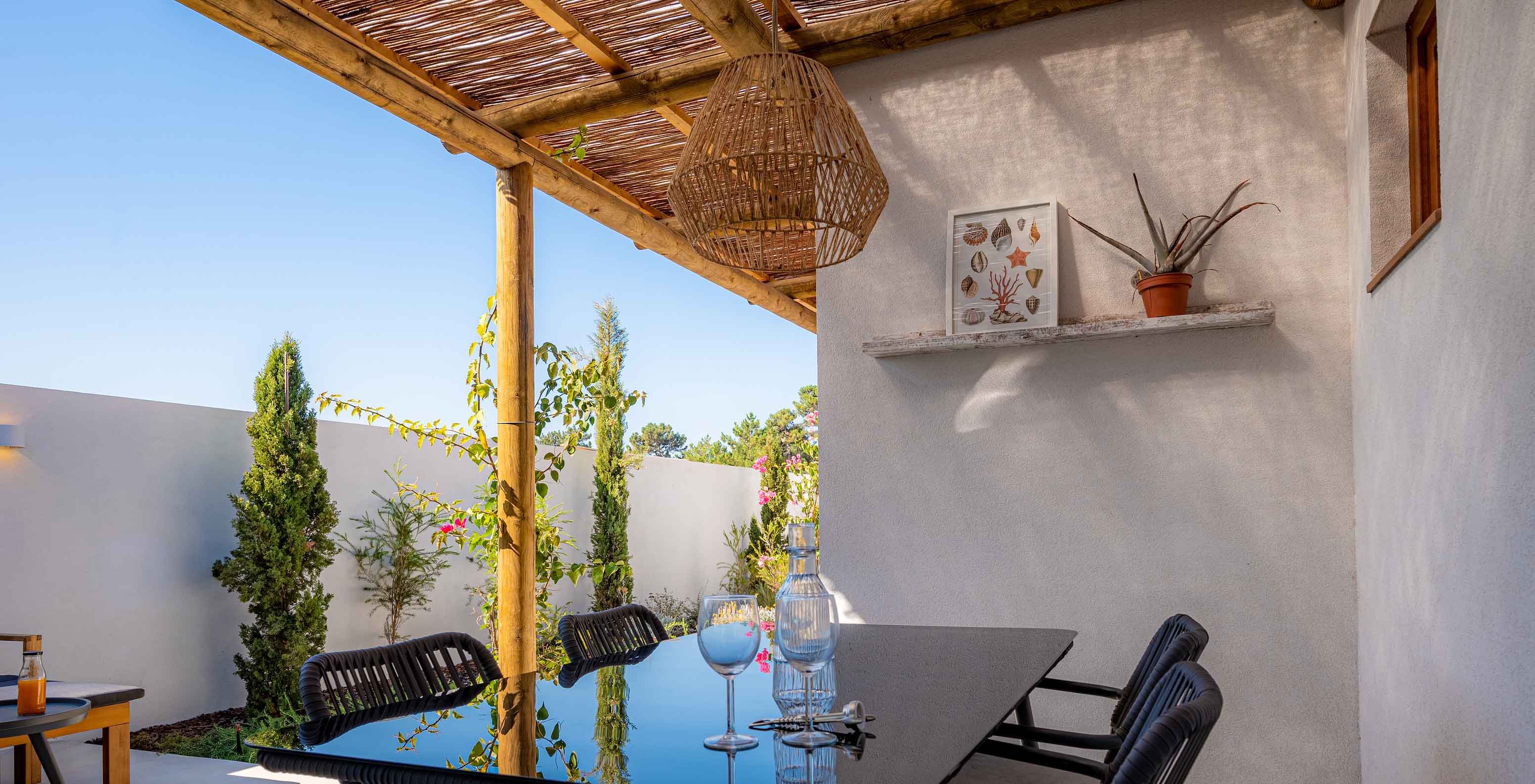 A Standard Villa T2 do Pestana Comporta Village Residences tem uma mesa de jantar ao ar livre debaixo de uma pérgola