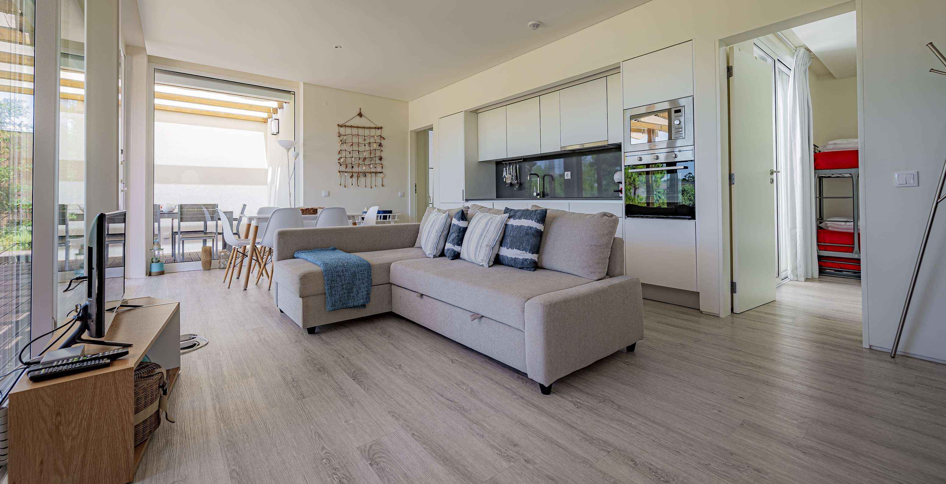 A Green Villa do Pestana Tróia Eco Resort tem uma sala junta com a cozinha, com sofá, mesa para jantar e televisão