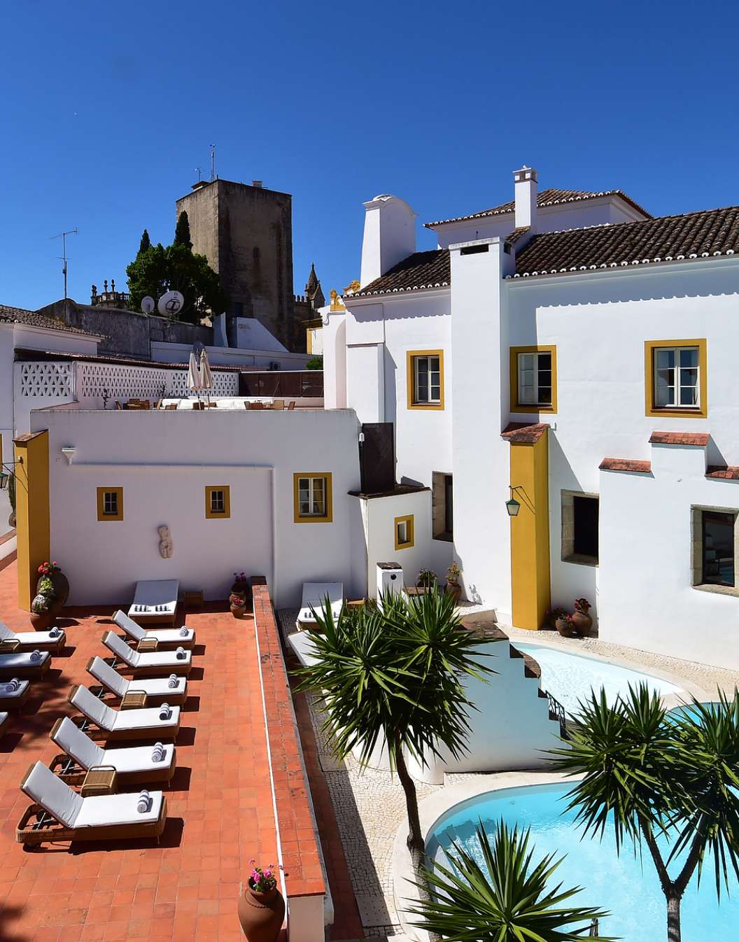 Vista da piscina, das espreguiçadeiras e do edifício da Pousada Convento de Évora, um Hotel com Piscina em Évora, Alentejo