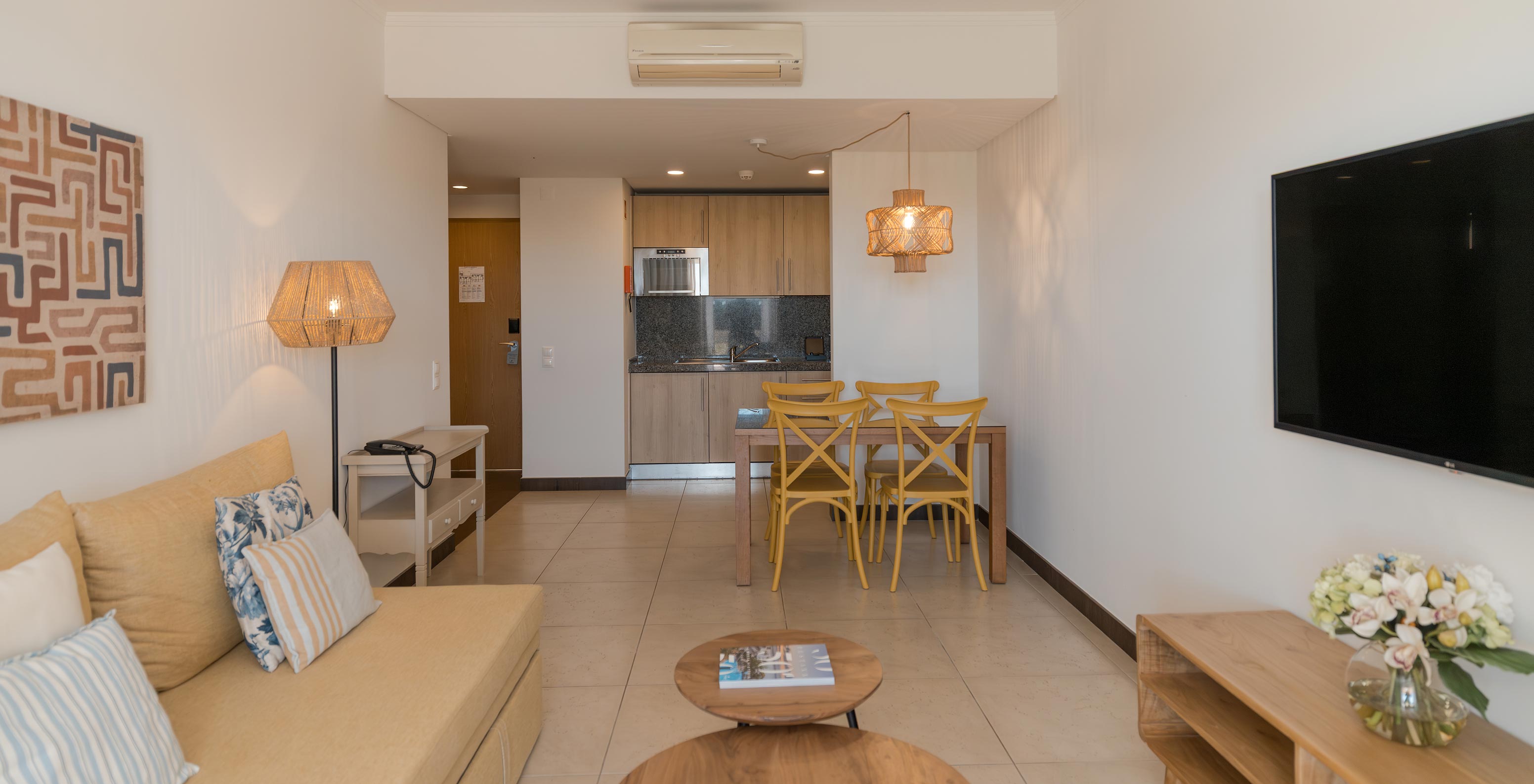 O Apartamento T1 Vista Jardim do Pestana Alvor Beach Villas tem uma sala de estar com sofá, televisão e mesa de jantar