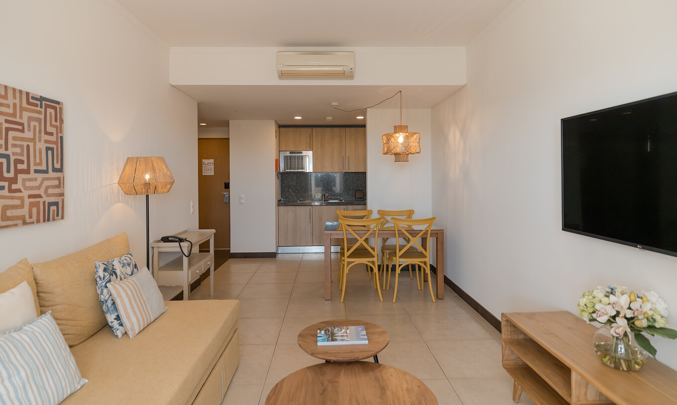 O Apartamento T1 Vista Jardim do Pestana Alvor Beach Villas tem uma sala de estar com sofá, televisão e mesa de jantar