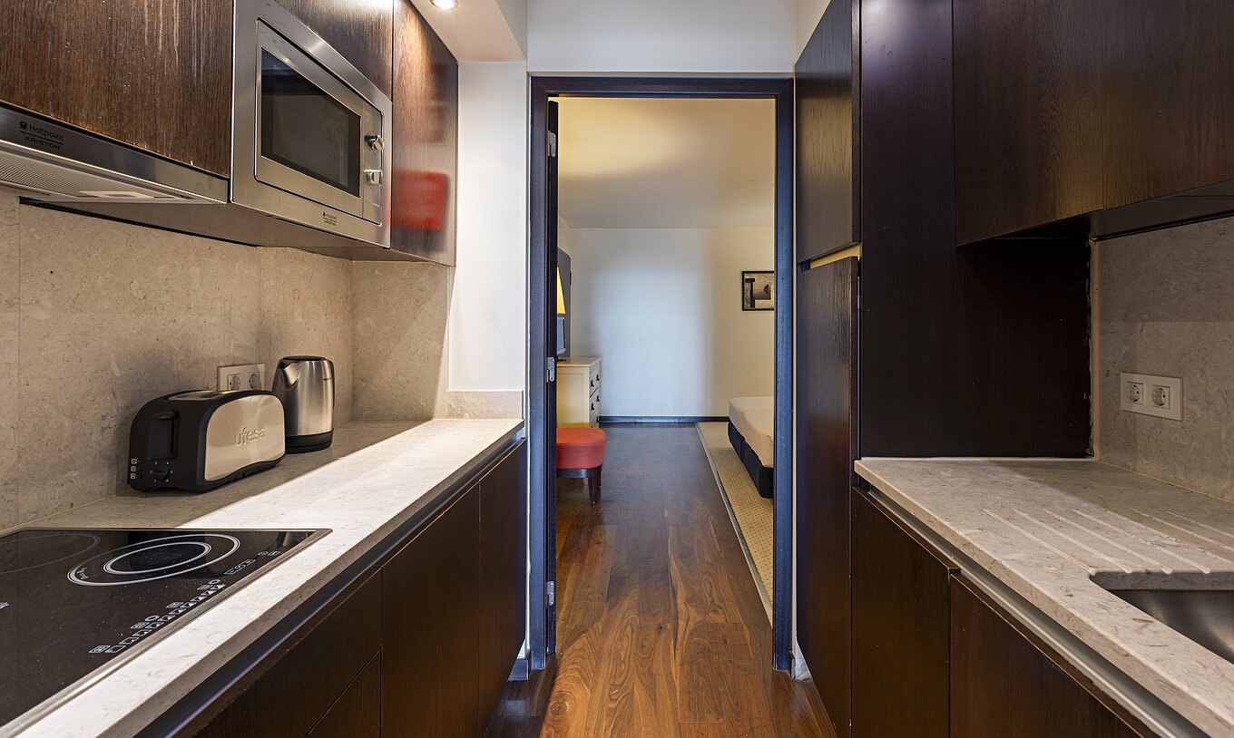 A Cliff Suite T2 do Pestana Alvor Praia tem uma cozinha equipada em madeira escura e pedra, com fogão e micro-ondas