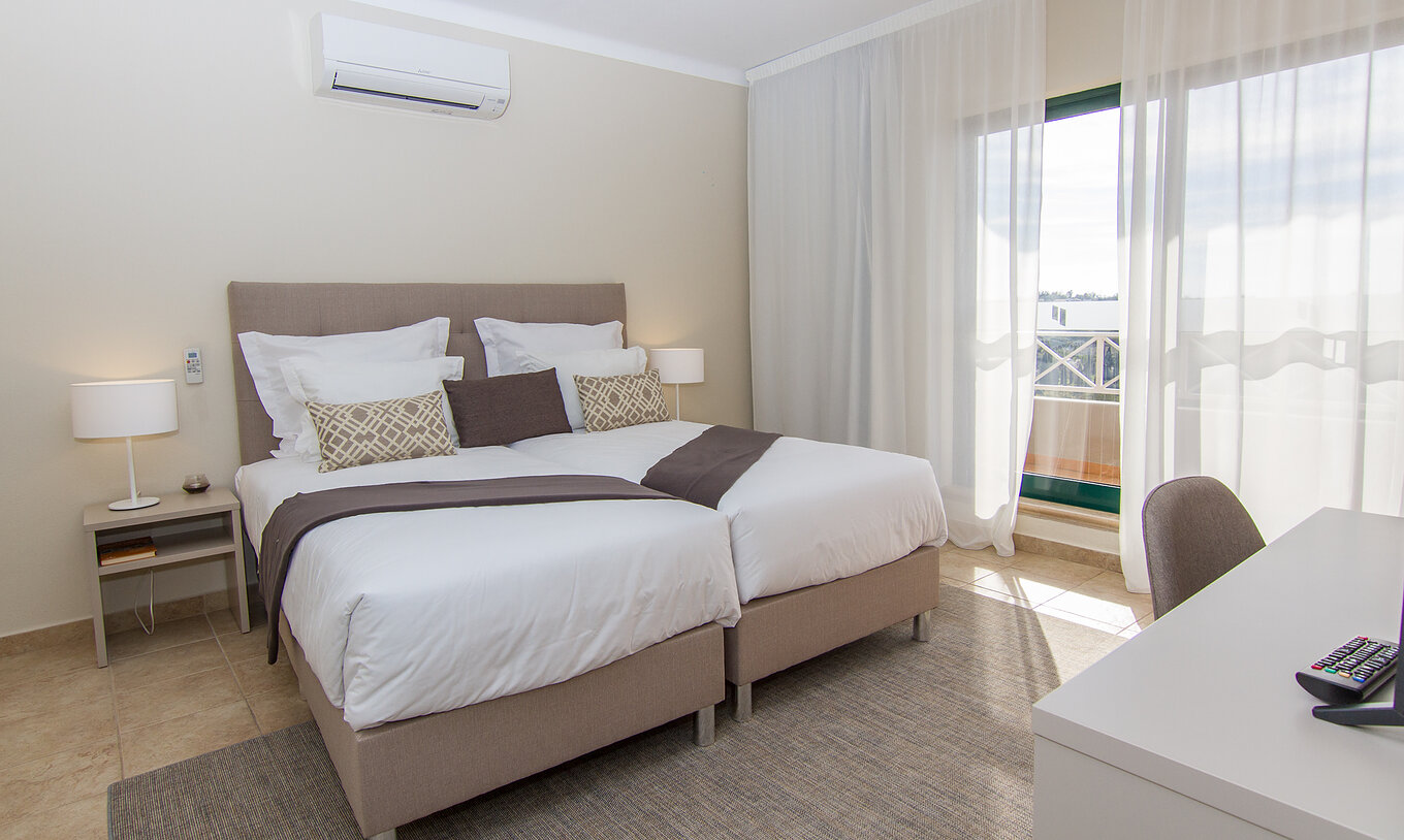 O Apartamento T2 do Pestana Gramacho Residences tem duas camas individuais, ar condicionado e uma janela com varanda
