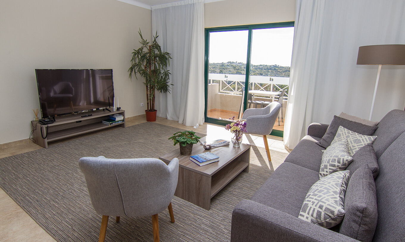 A Villa V3 do Pestana Gramacho Residences tem uma sala de estar com sofás, televisão e uma janela com varanda