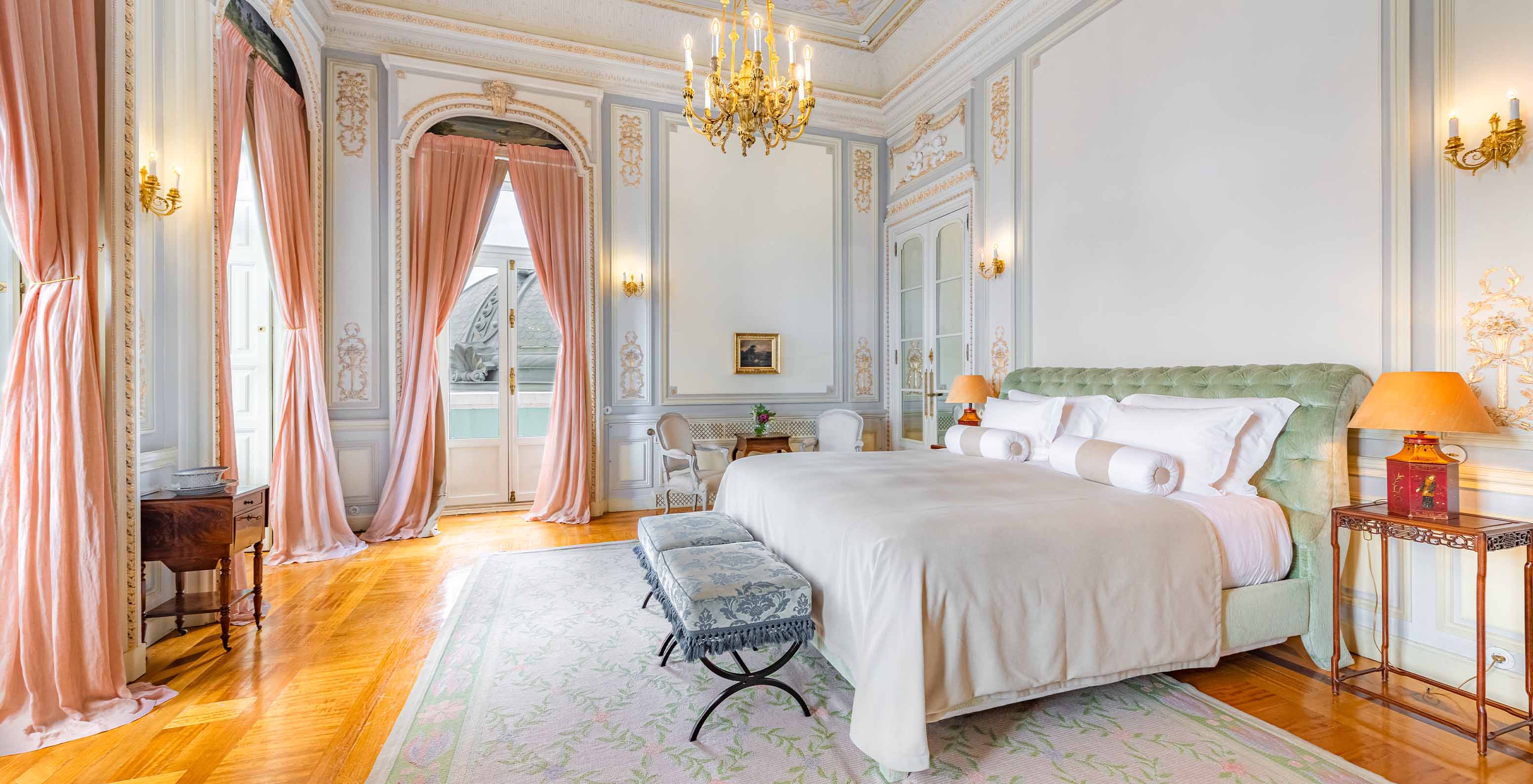 A Suite D. Manuel do Pestana Palace Lisboa tem um quarto grande e luxuoso com cama de casal e lustre dourado