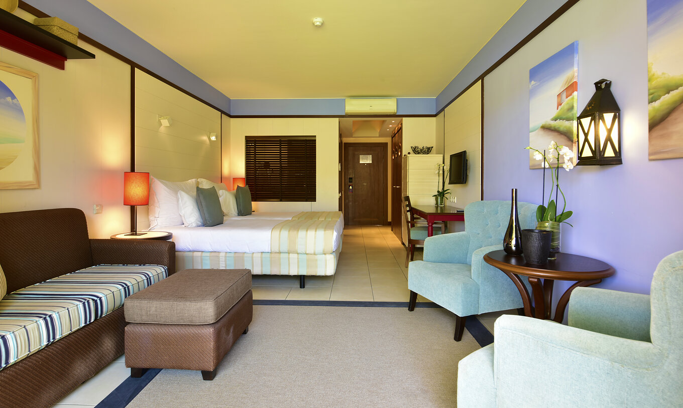 O Duplo Vista Piscina do Pestana Porto Santo All Inclusive tem um sofá, duas poltronas, duas camas, televisão e secretária