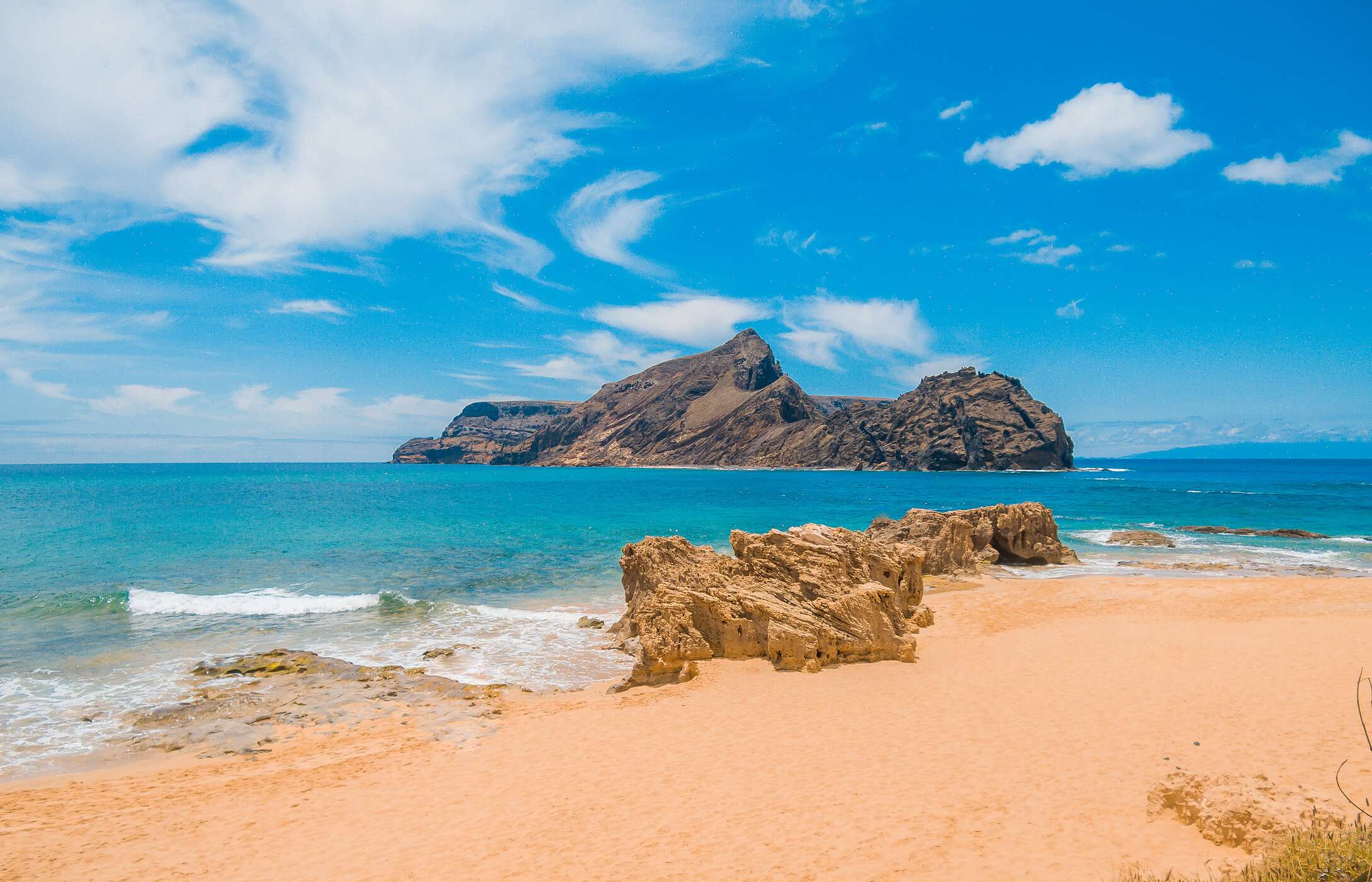 Praia de Porto Santo, com areias douradas e águas cristalinas com uma segunda ilha em segundo plano