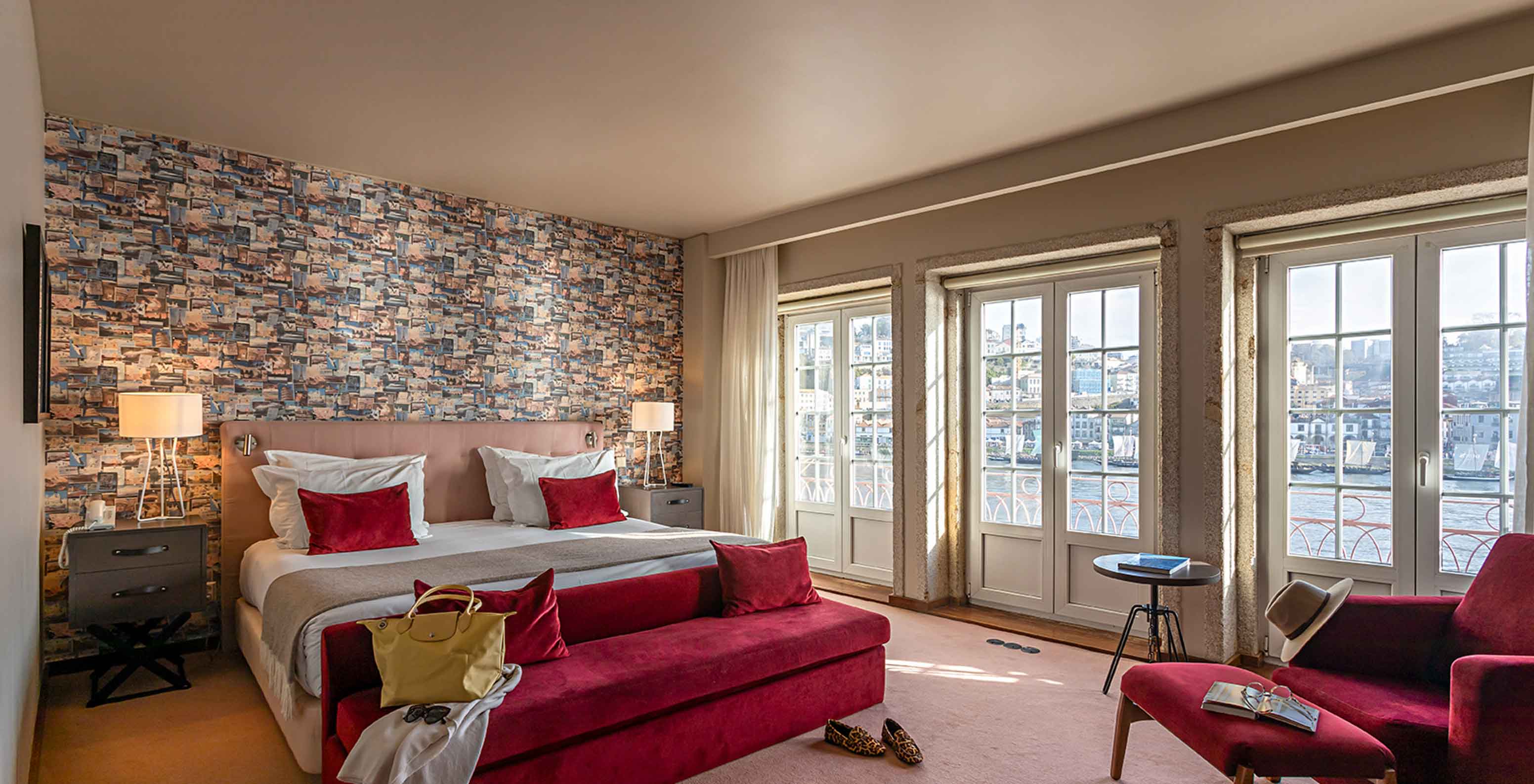 A Suite Grand View do Pestana Vintage Porto tem uma cama de casal, um sofá vermelho e janelas com vista para o Porto