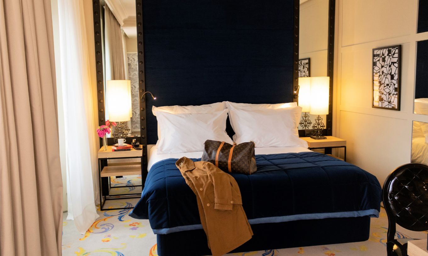 O Quarto Superior Plus do Pestana Plaza Mayor Madrid tem uma cama de casal com uma mala e um casaco em cima da cama