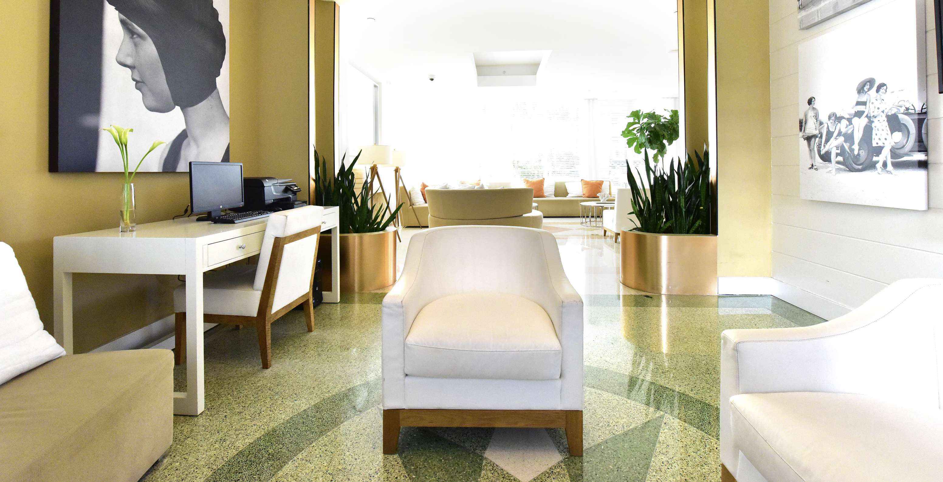 Área de trabalho no lobby do hotel equipada com computador, fotocopiadora, secretária e cadeiras