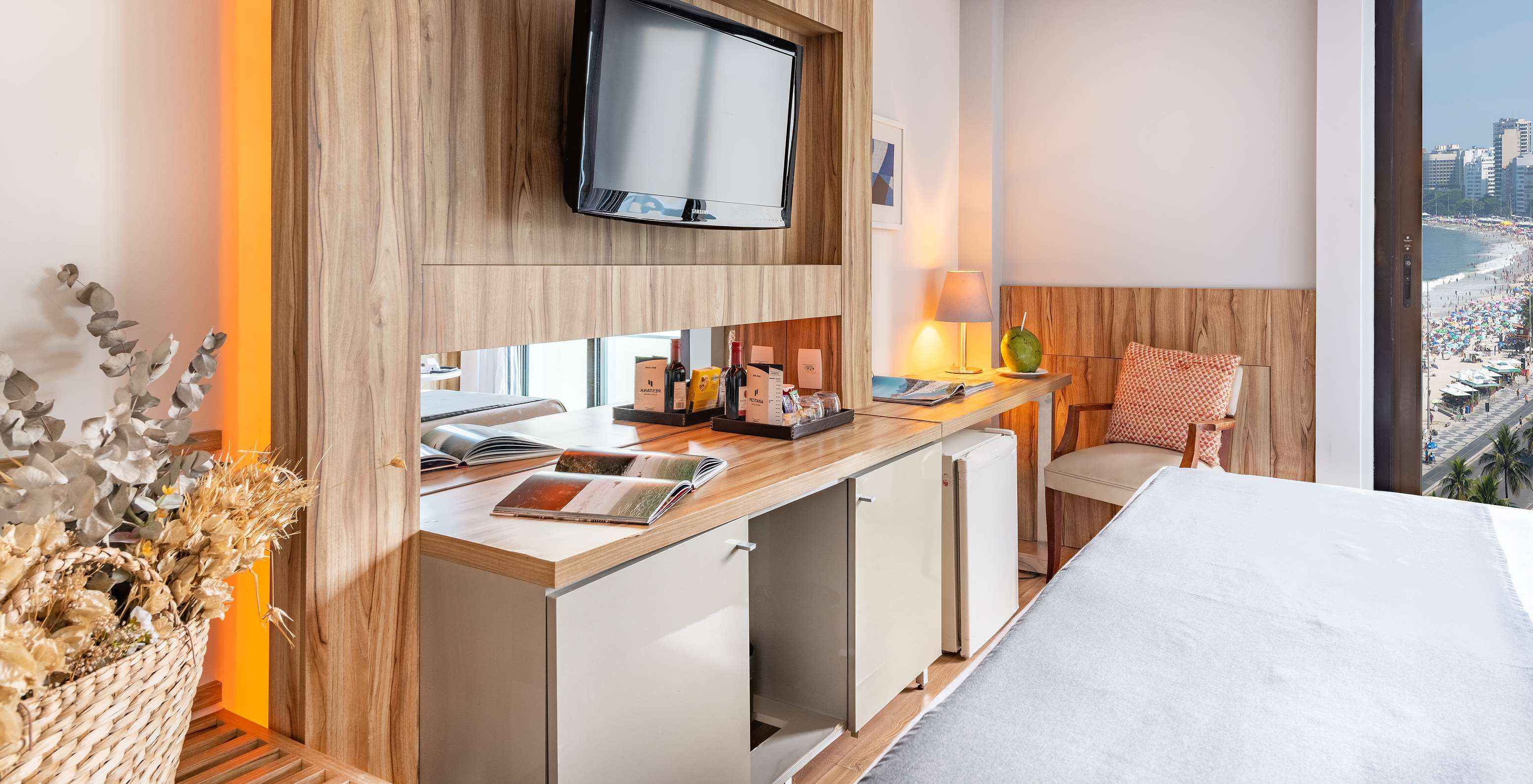 O Queen Vista Lateral Mar do Pestana Rio Atlântica tem uma televisão em frente à cama e uma cadeira almofadada